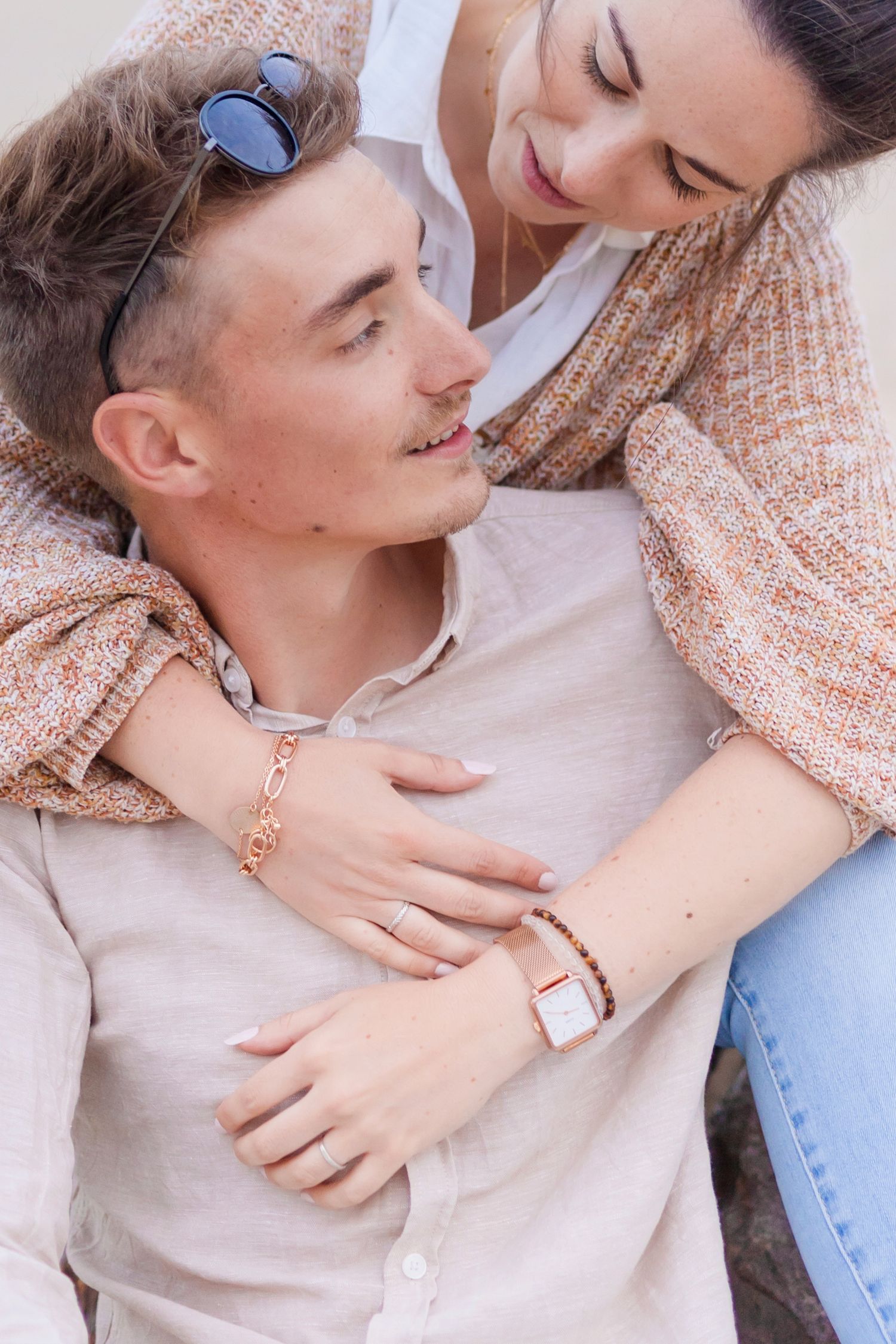 Intimate close-up moment shared between couple outdoors with sunglasses visible.