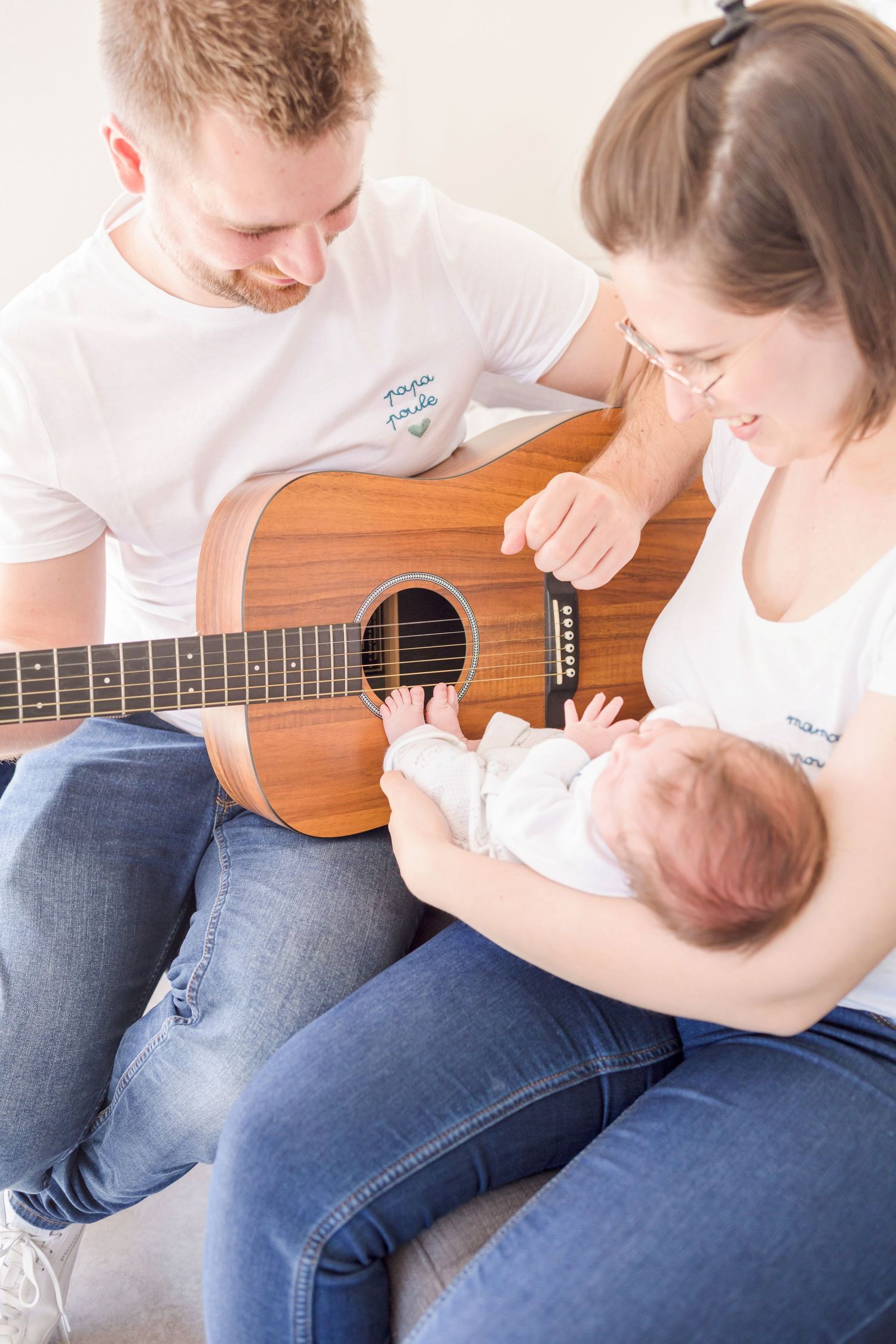 Family sharing a musical moment together on a grey couch while playing ukulele.