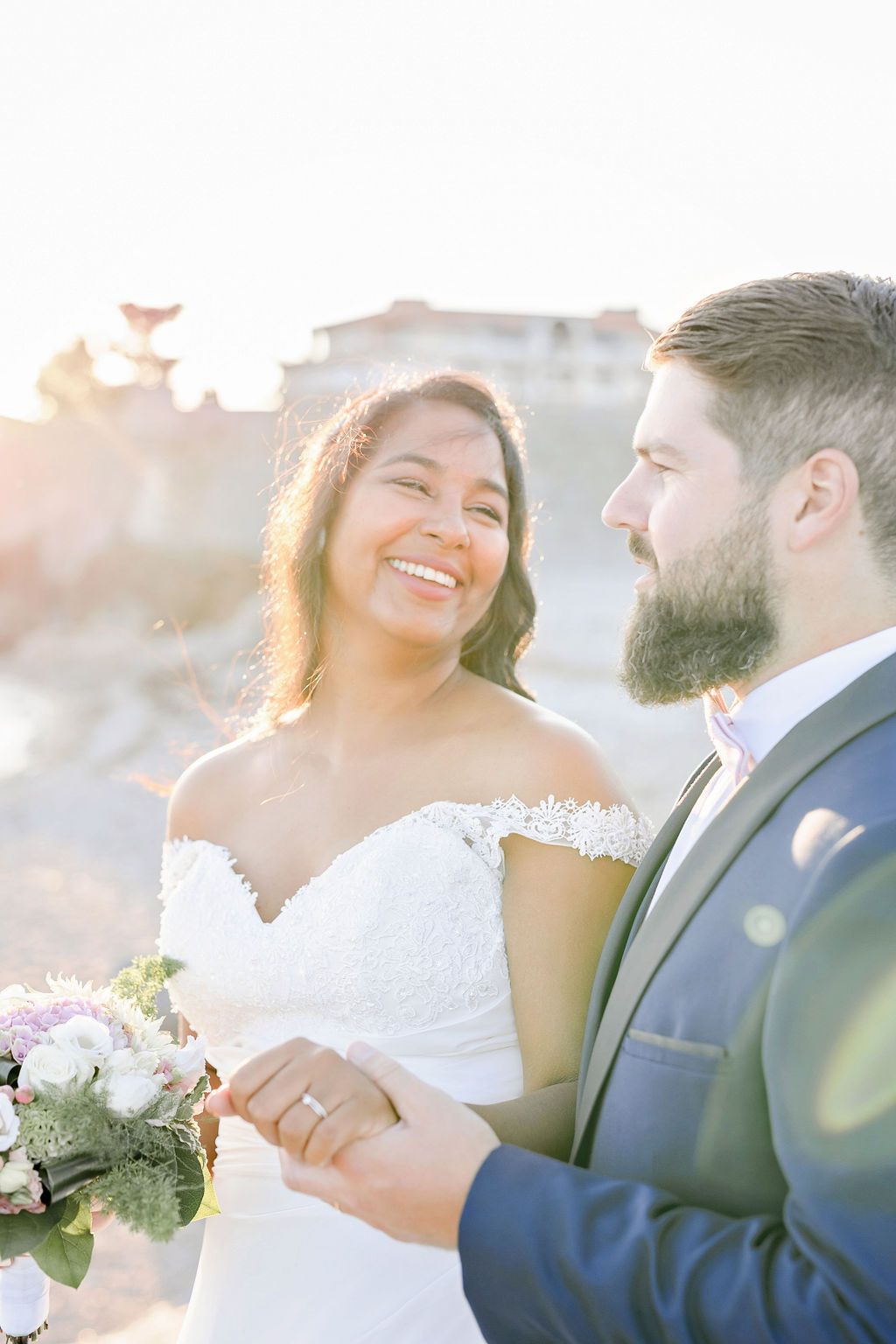 Wedding couple embraces in soft golden light during intimate outdoor photo session.
