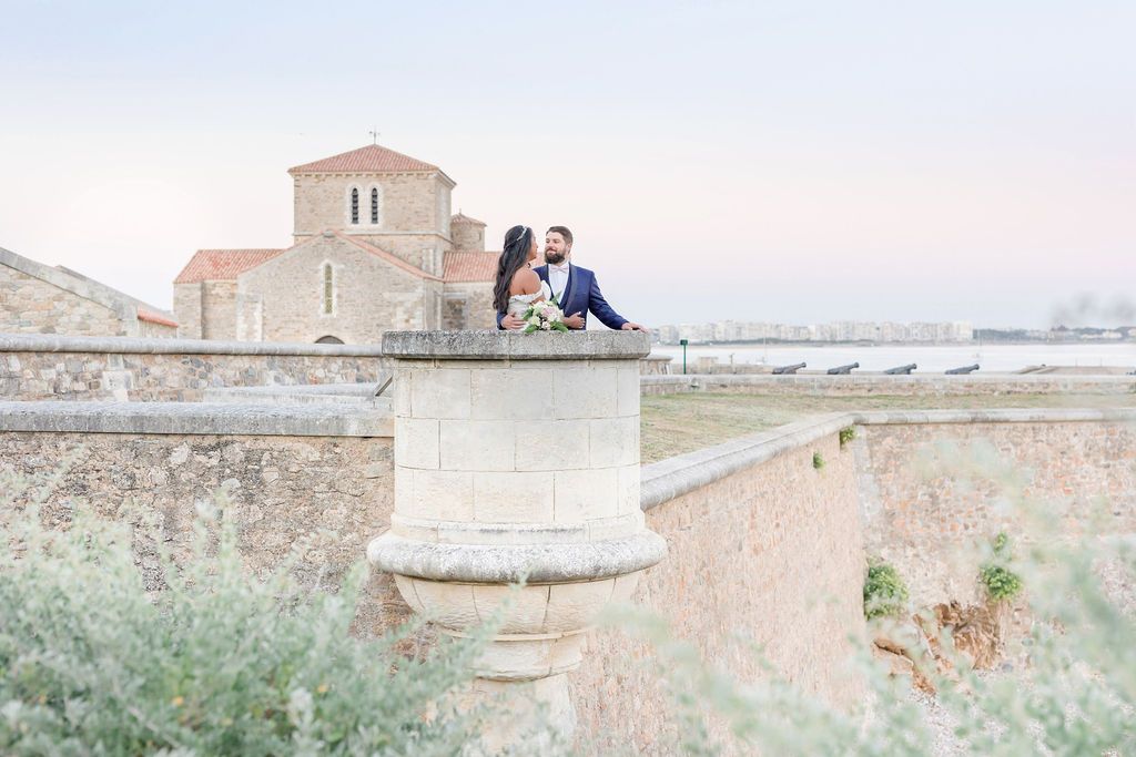 Romantic moment captured on ancient stone fortifications with Mediterranean church in background.