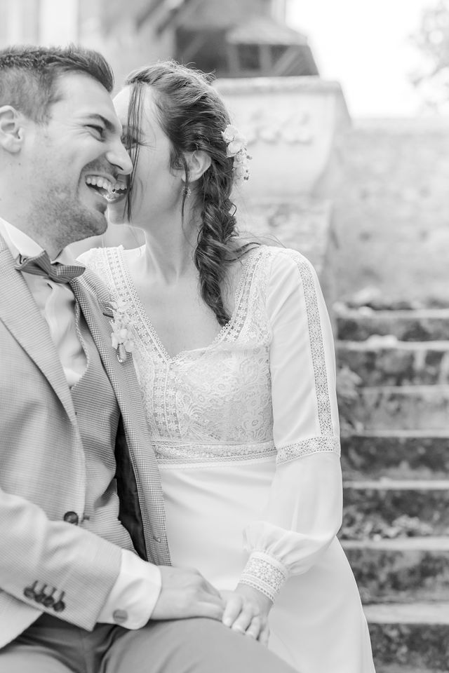 Intimate black and white portrait of couple sharing joyful moment on stone steps.