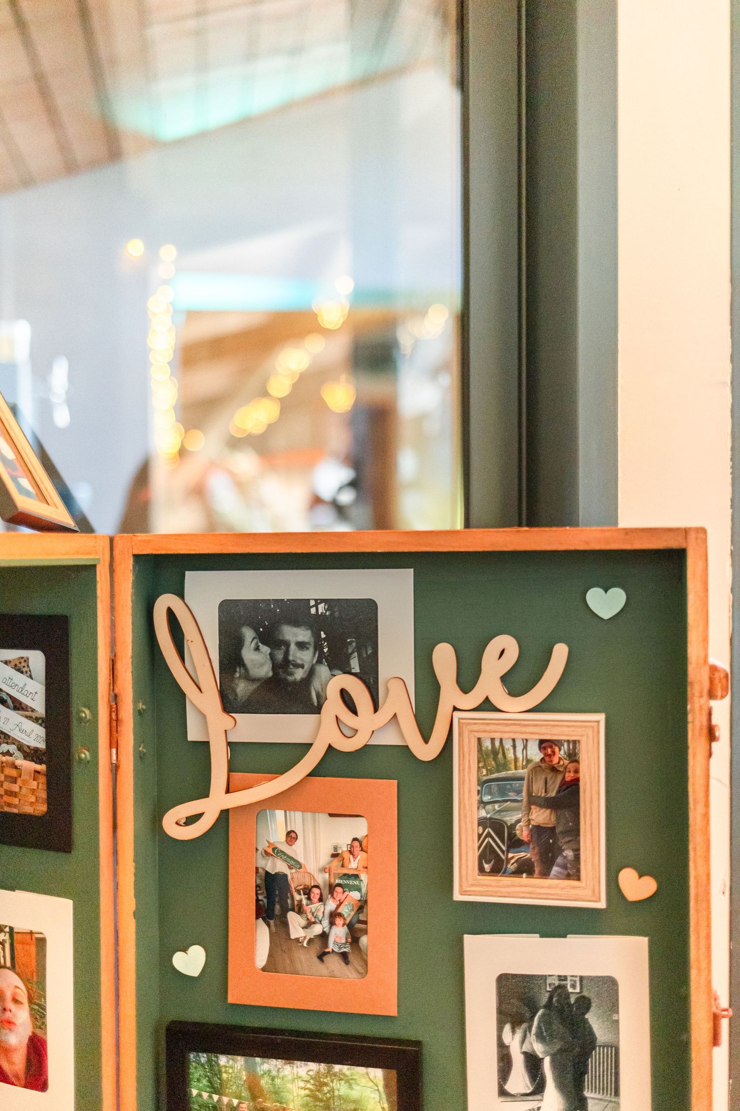 Wooden photo display board with 'Love' text and heart decorations featuring multiple framed photographs.