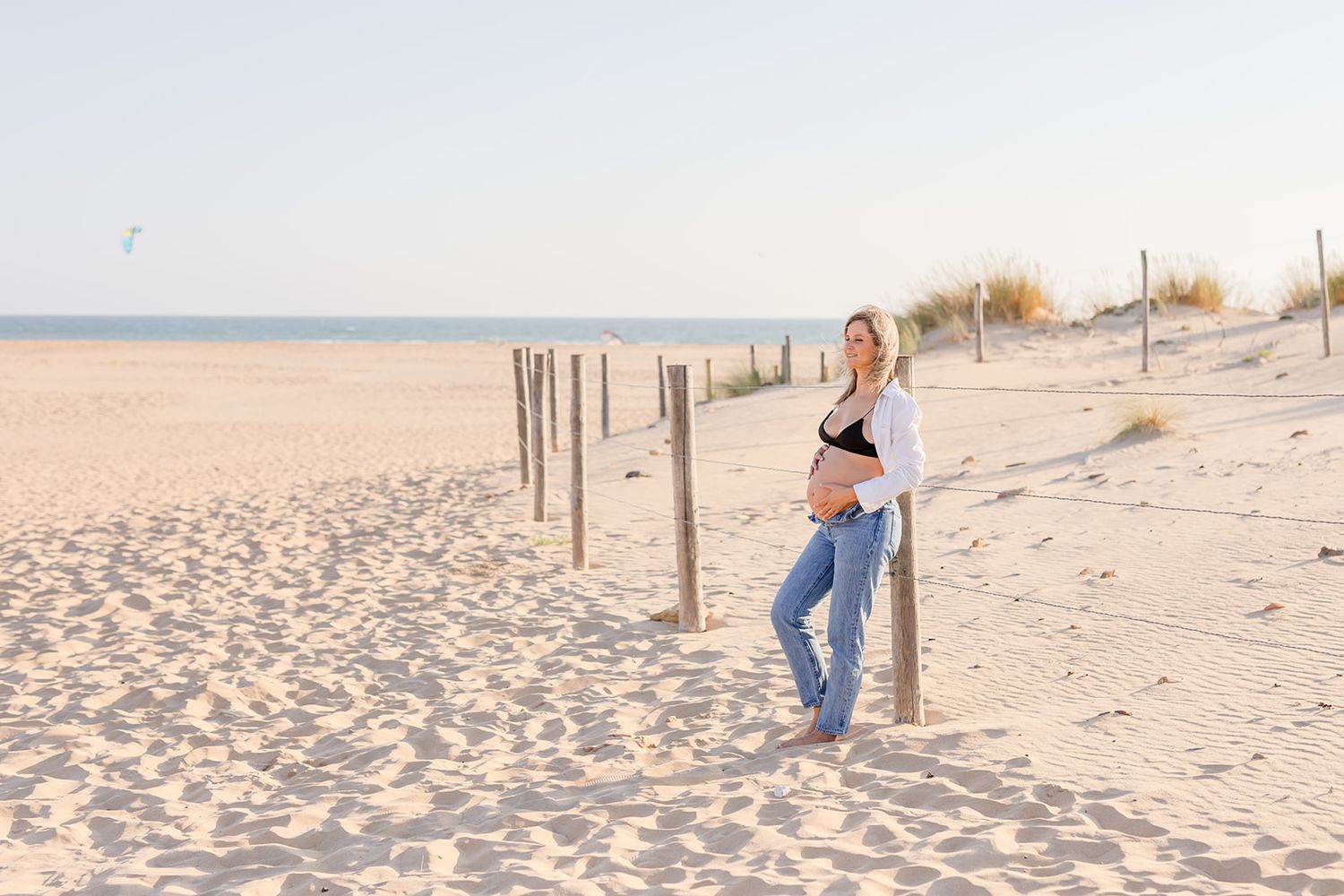 Family photos on a bright sandy beach with seagrass and coastal dunes during golden hour at sunset.