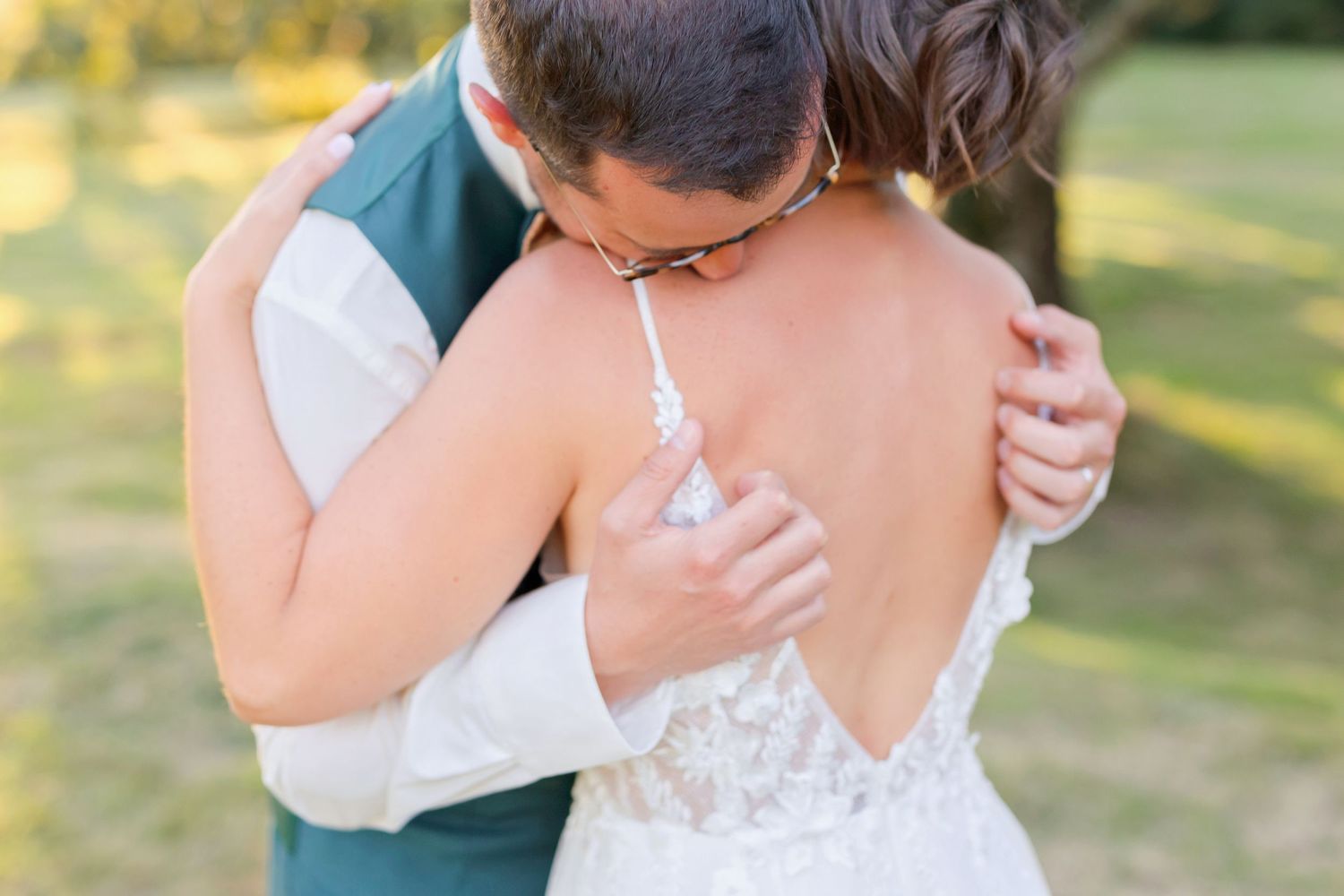 Close-up of couple embracing showing intricate lace details on wedding dress.