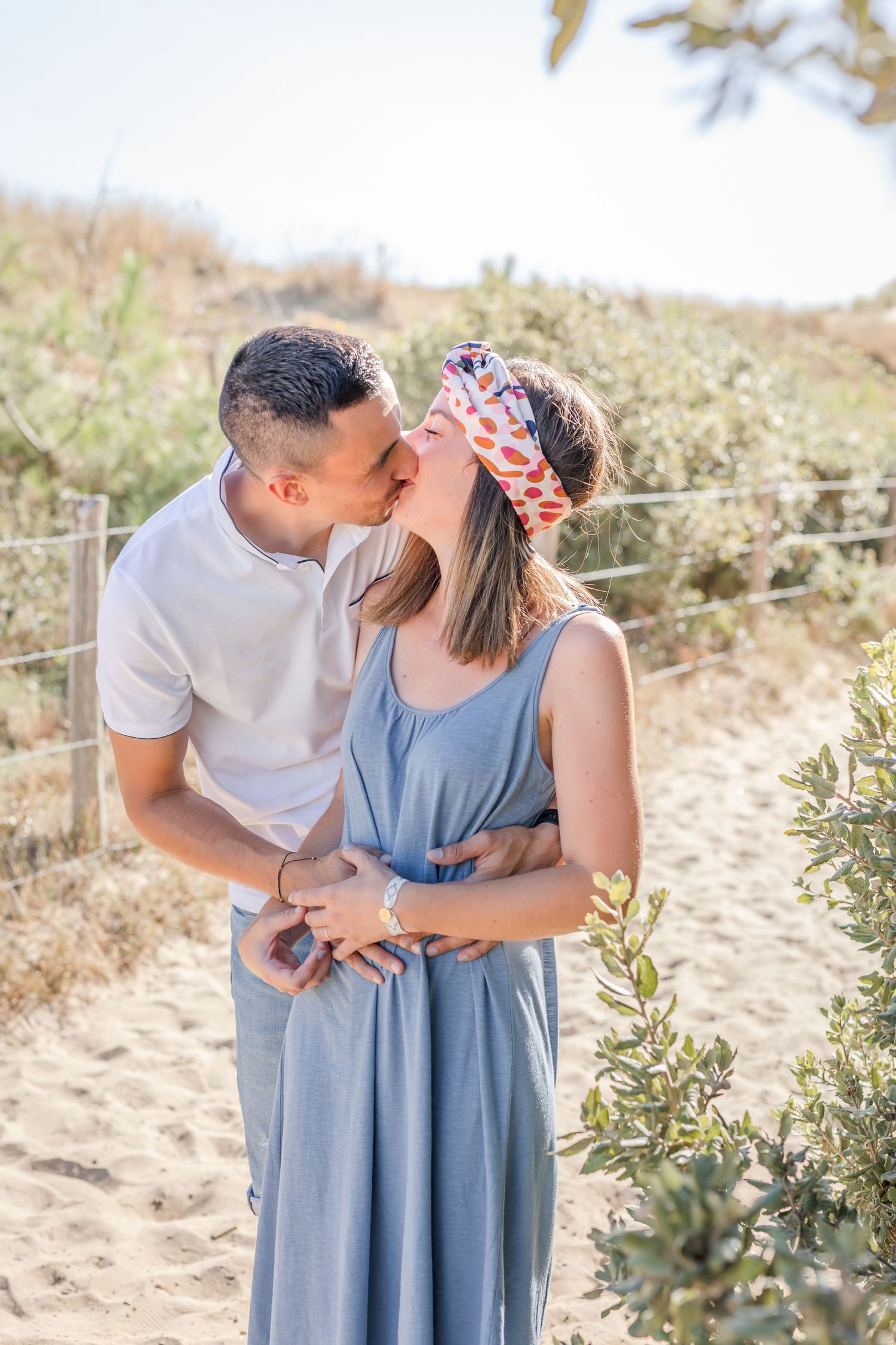 Sweet couple embracing on sandy beach pathway during golden hour photography session.