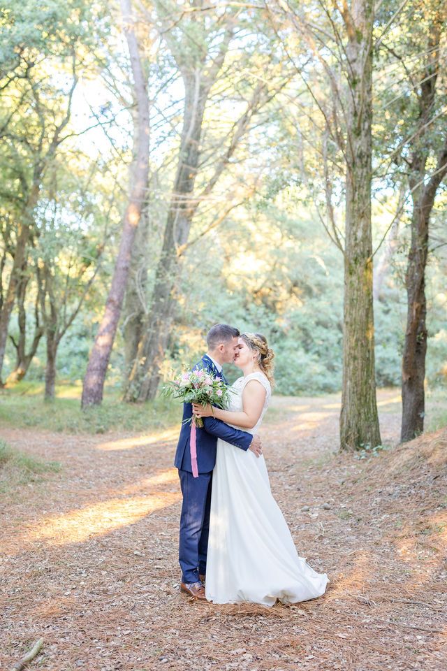 A couple shares an intimate dance moment in a wooded setting with golden sunlight filtering through trees.