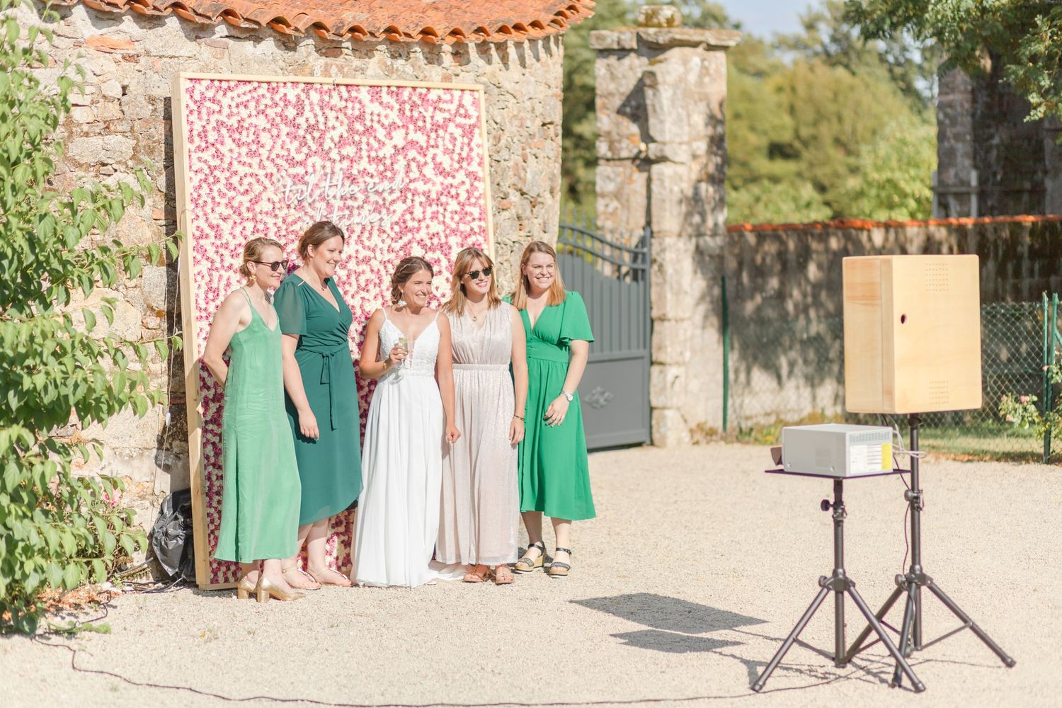 Wedding party posing against stone wall at outdoor venue.
