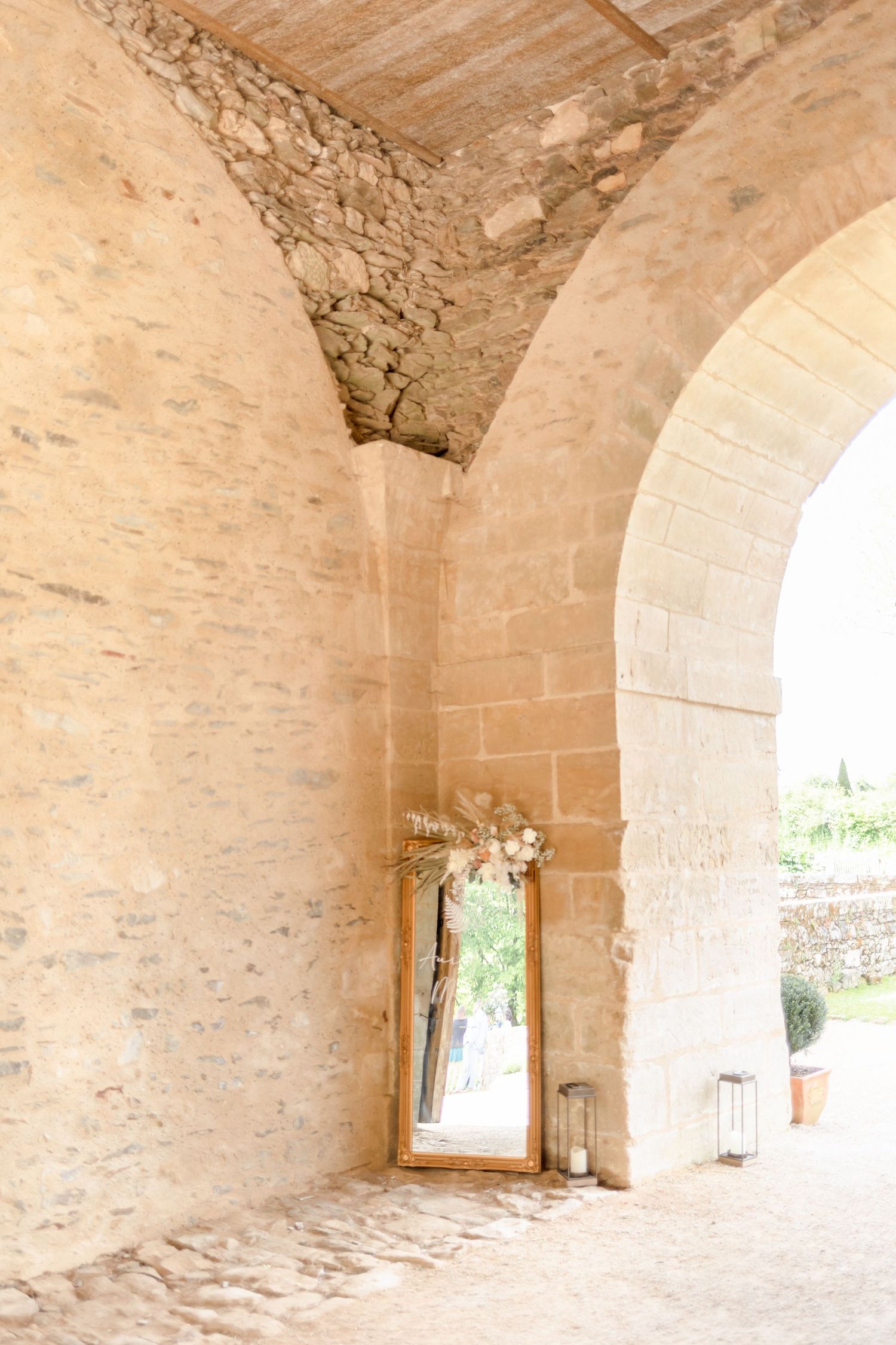 Stone archways provide a rustic passageway through a Mediterranean style building with natural lighting.