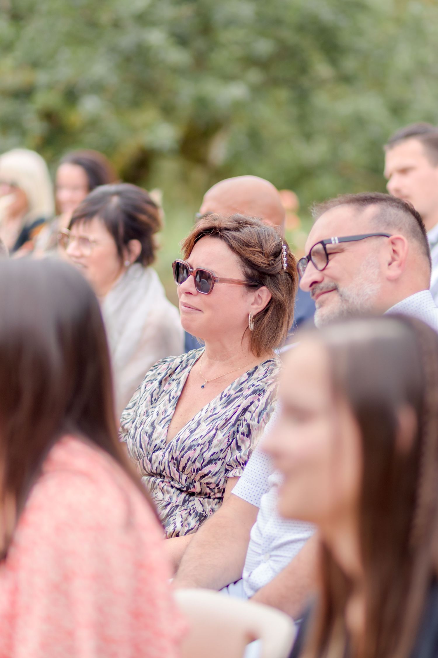 Wedding guests watching ceremony in outdoor garden setting.