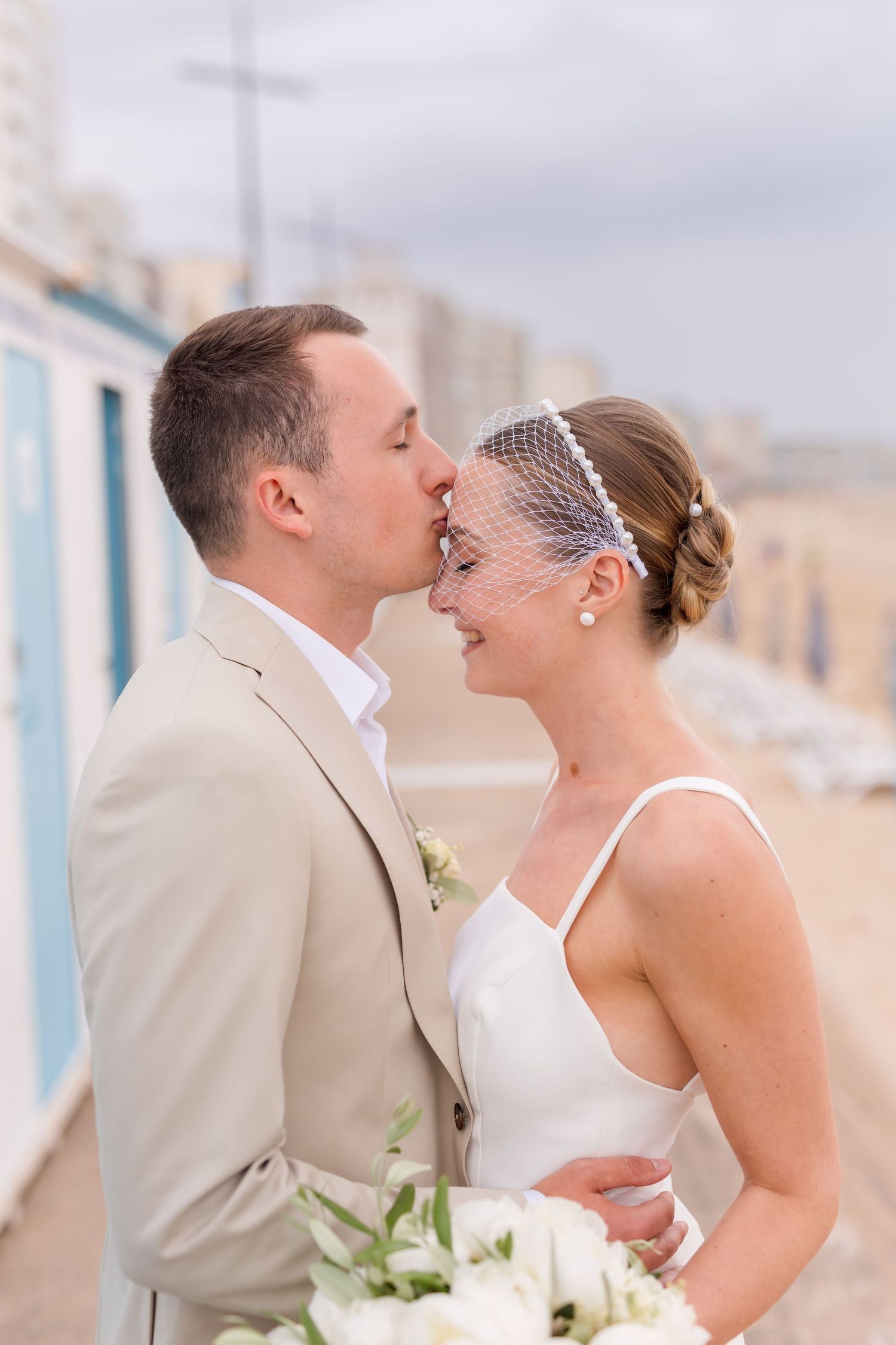An intimate wedding portrait by blue beach huts with white floral bouquet.