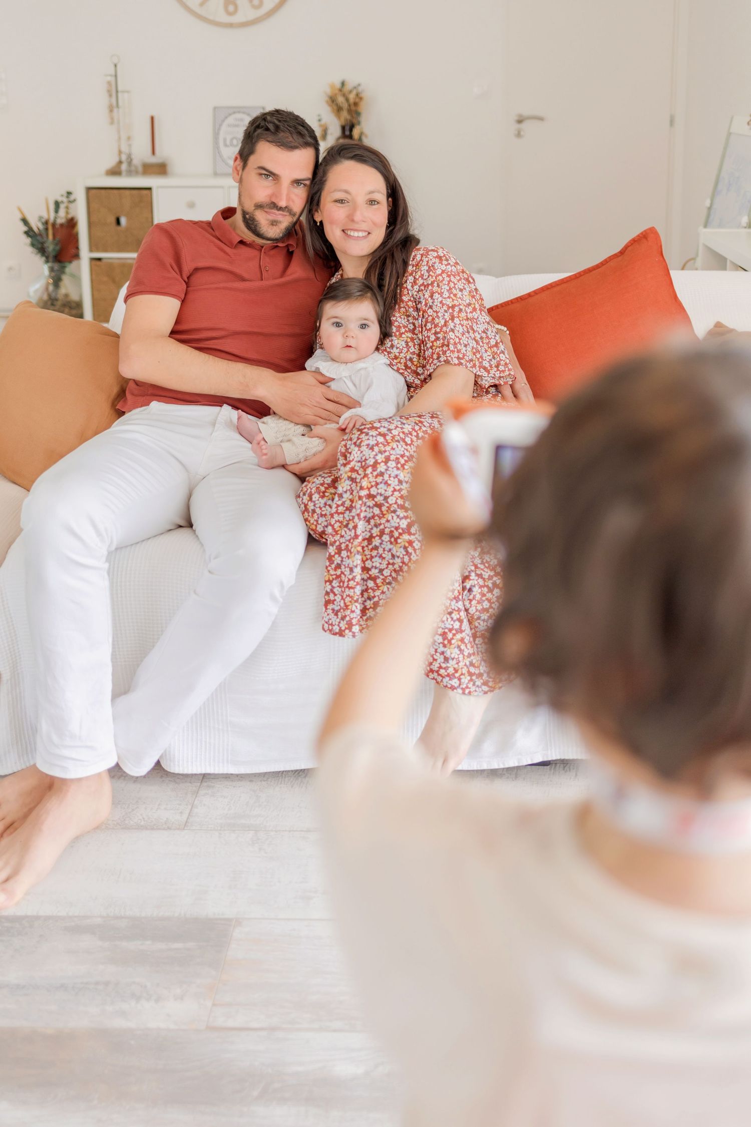 Candid family photography in bright white room with rust-colored accents.
