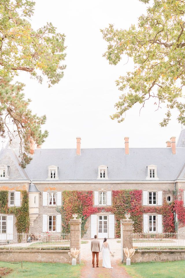 Elegant chateau wedding venue with red ivy and white windows captured in soft, dreamy light.