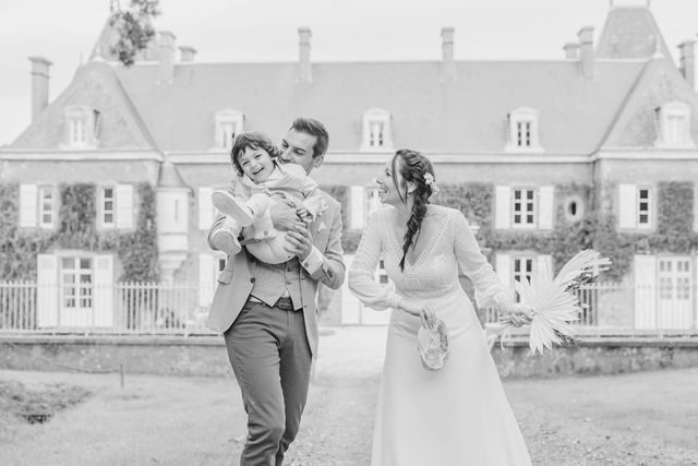 Black and white photo of a joyful moment outside a French chateau with ivy-covered walls.