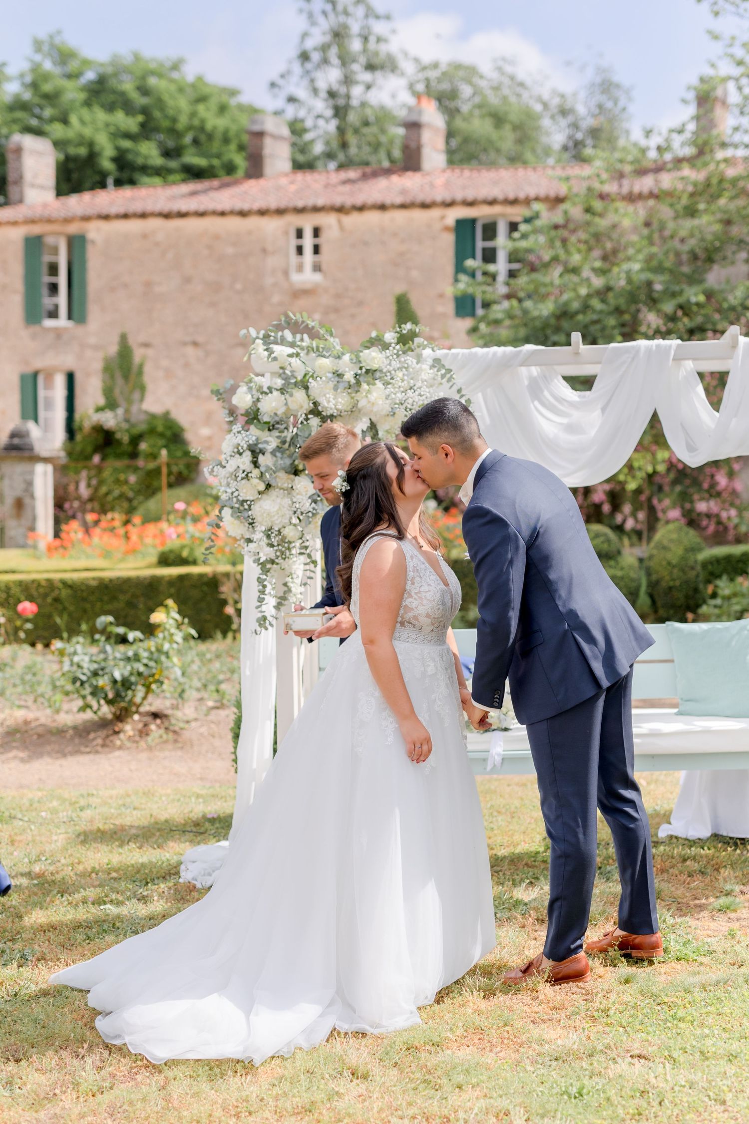 Romantic wedding ceremony moment under floral arch in garden setting.