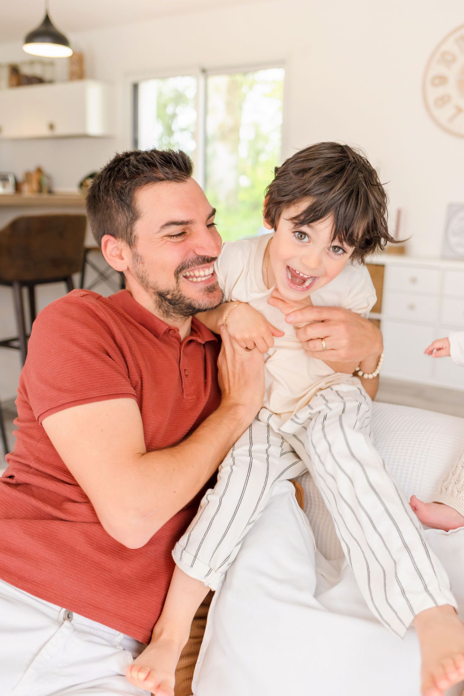 Family members sharing playful moments and laughter in a bright, modern living space.