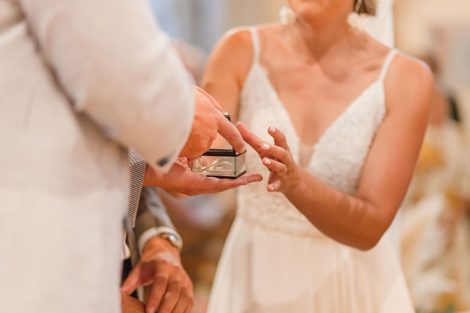 Close-up of hands during ring exchange at wedding ceremony.