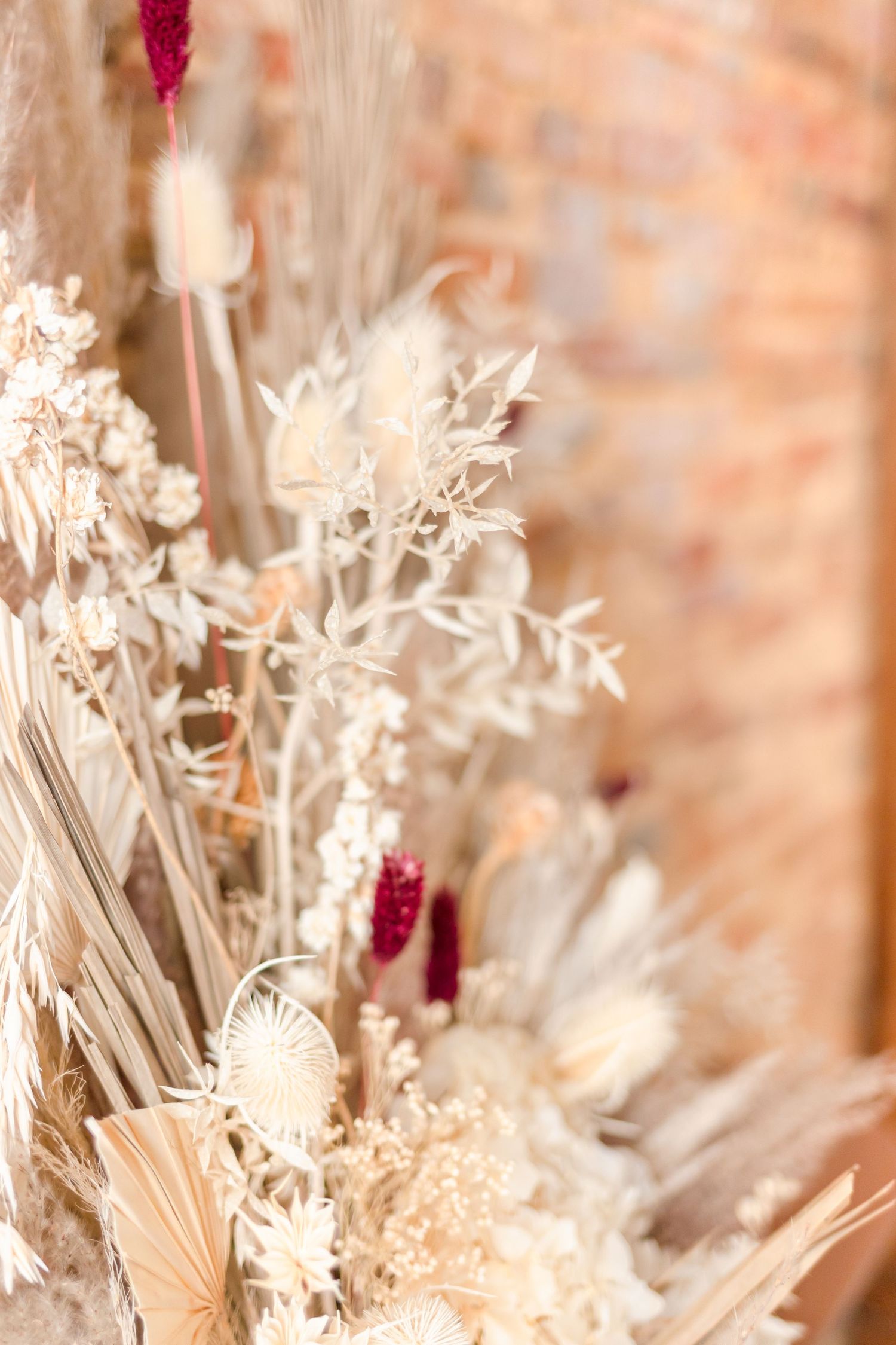 Close-up of delicate dried flowers and pampas grass in muted beige and burgundy tones.
