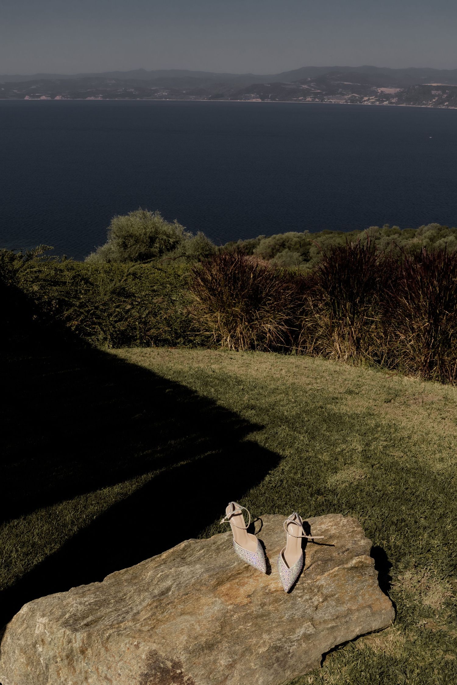 Wedding rings placed on a rocky overlook with coastal ocean views in the background.