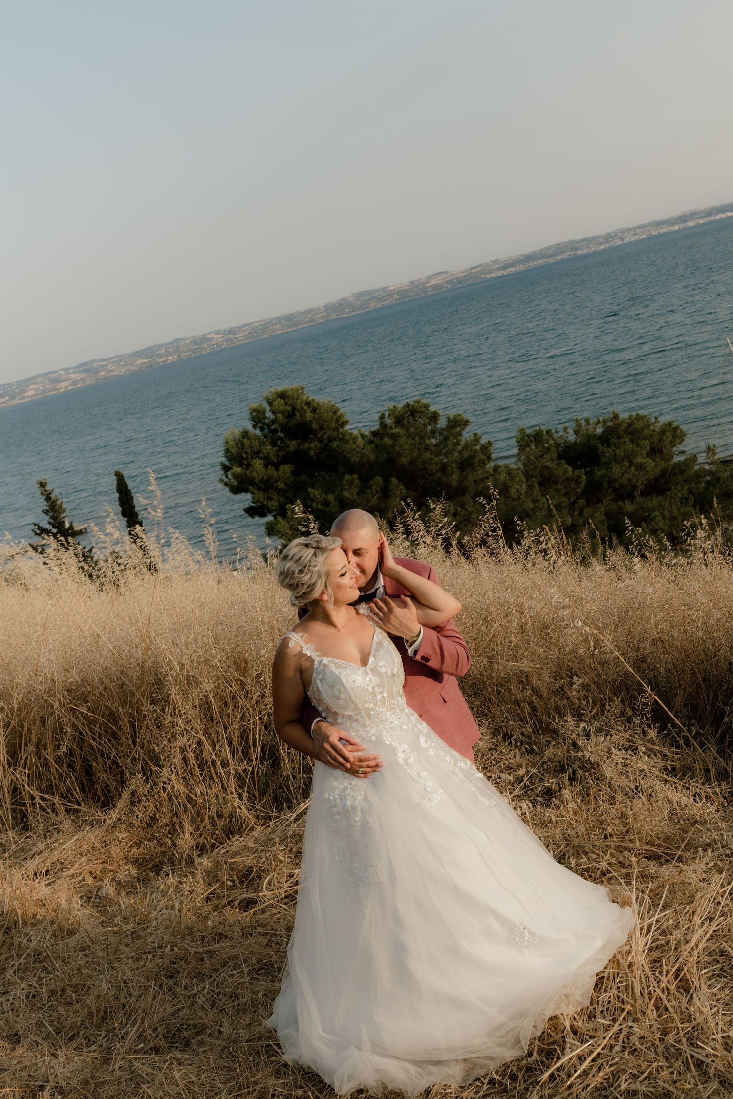 Coastal wedding portraits with tall grass and ocean views at golden hour.