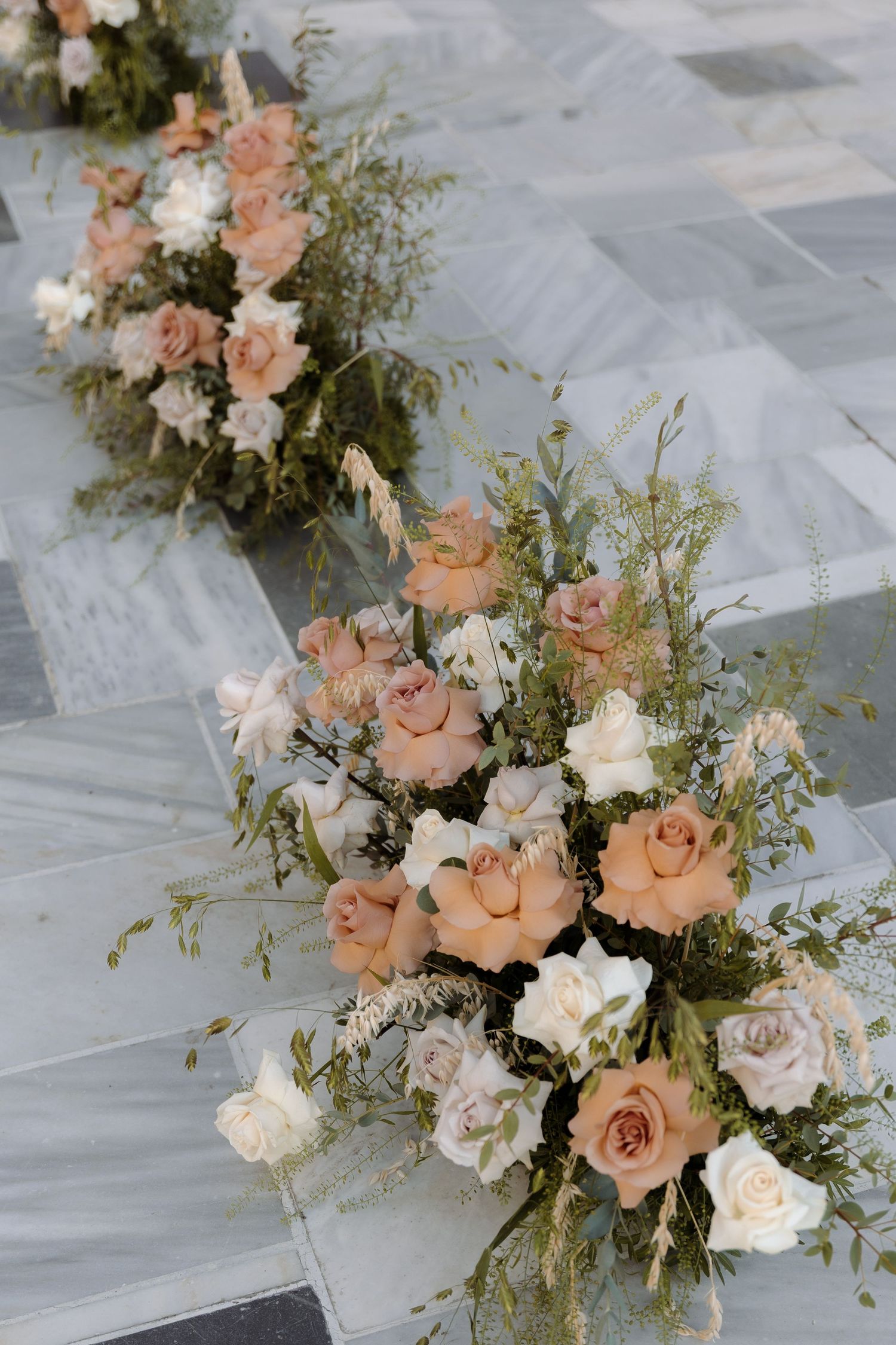 Elegant floral arrangement with peach roses and white flowers cascading on grey marble.