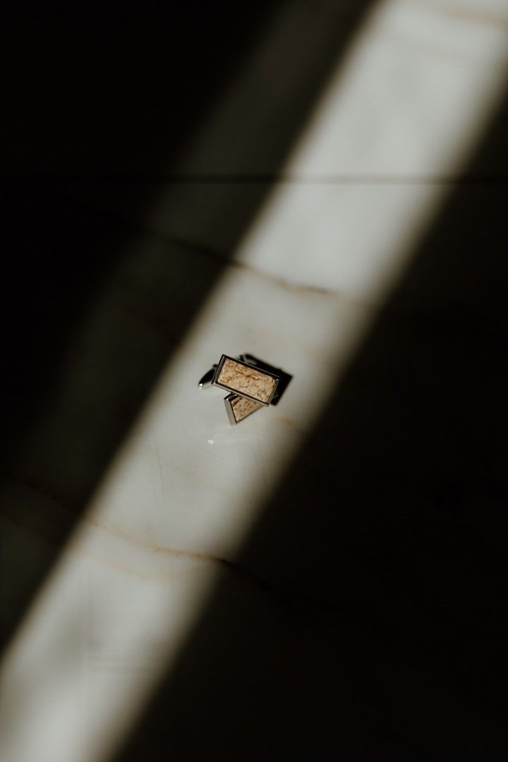 Minimalist photo of a small pin or brooch casting shadow in dramatic lighting.