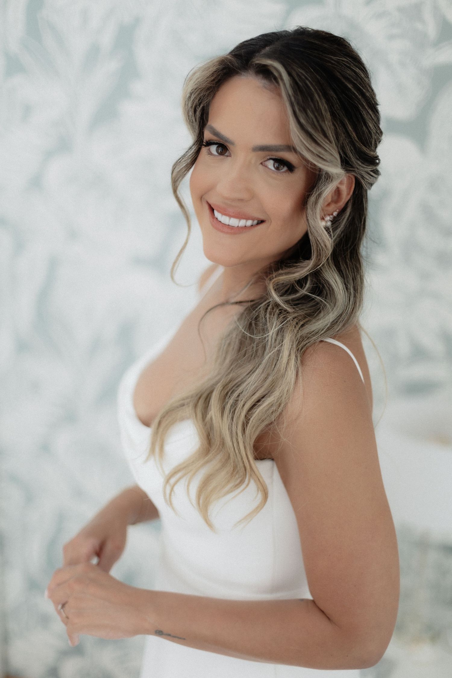 Elegant bridal portrait featuring soft waves and natural makeup against a light background.
