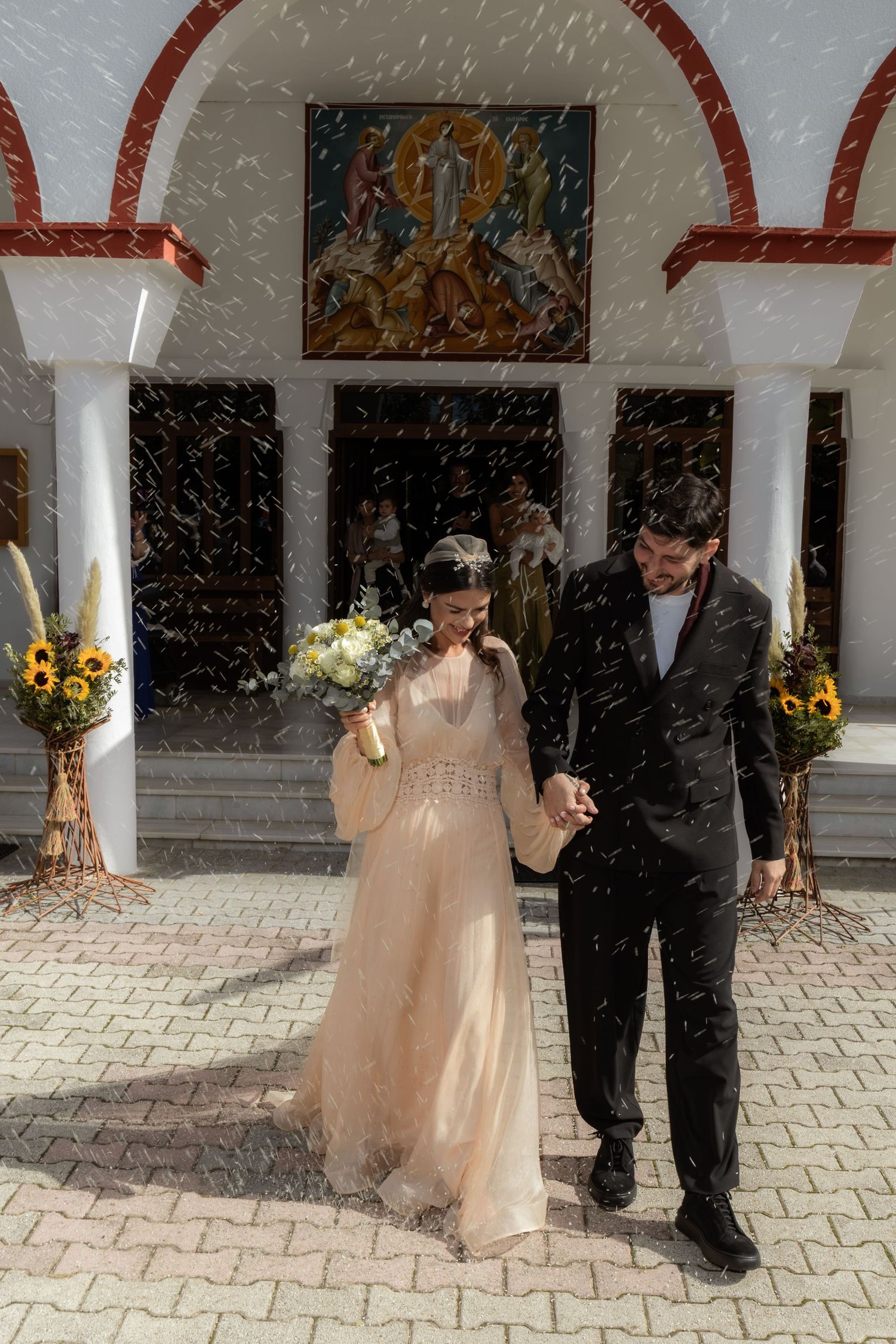 Wedding celebration with snowfall effect against arched colonnade background.