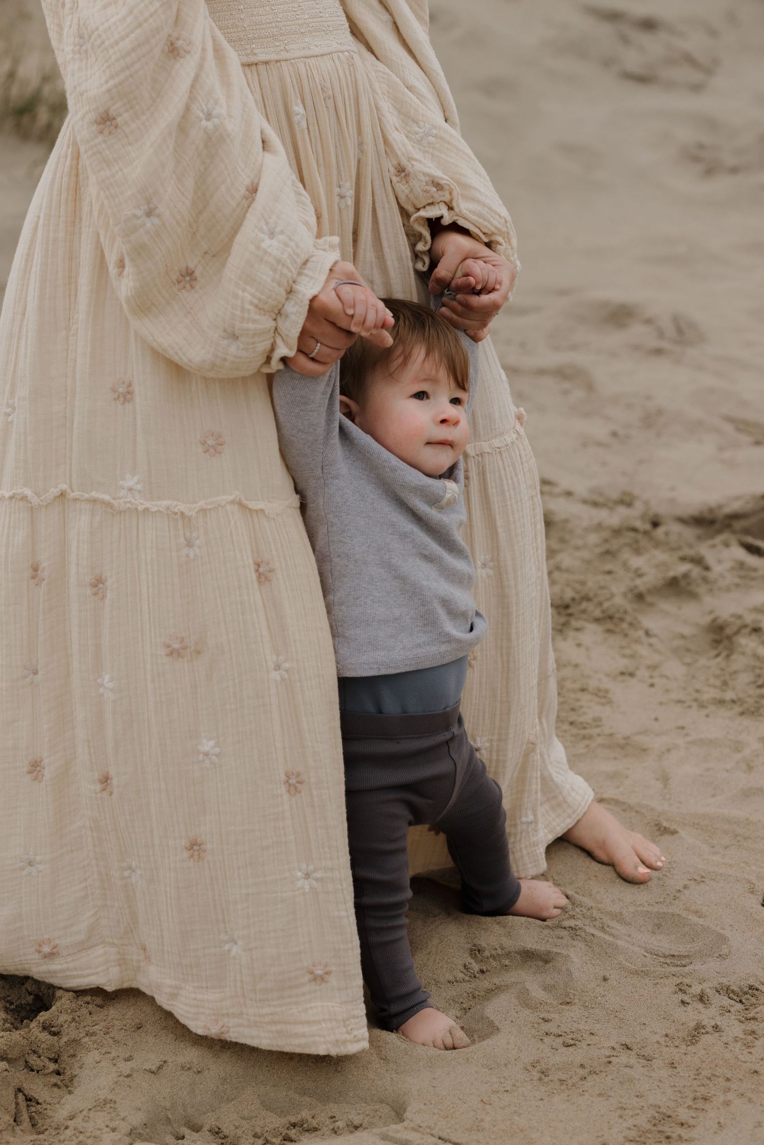 Bare feet walk on sandy beach with flowy cream dress and gray clothing visible in cropped shots.