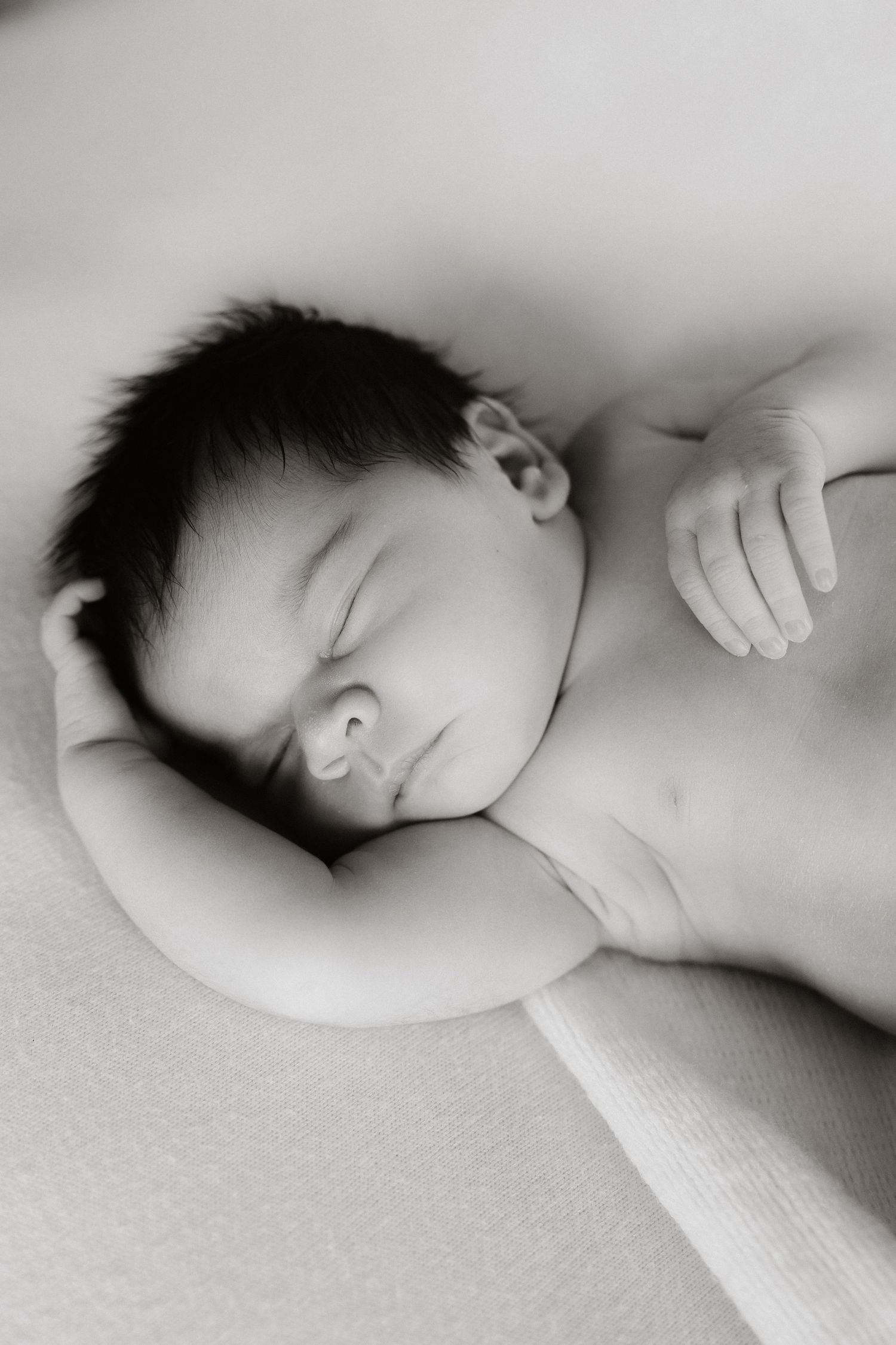 A peaceful black and white portrait of a sleeping newborn baby.
