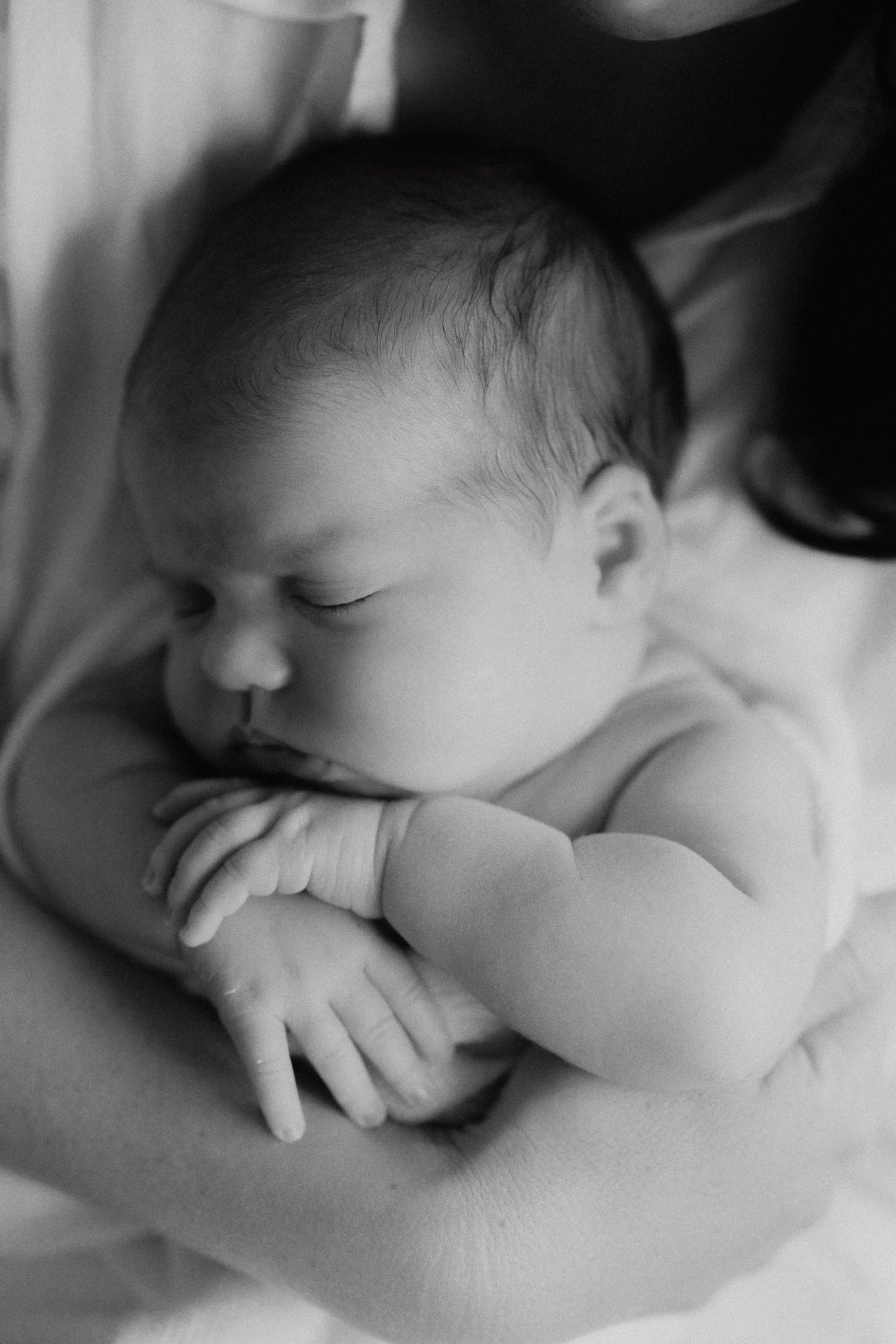 Peaceful sleeping newborn baby in black and white photography with soft lighting.