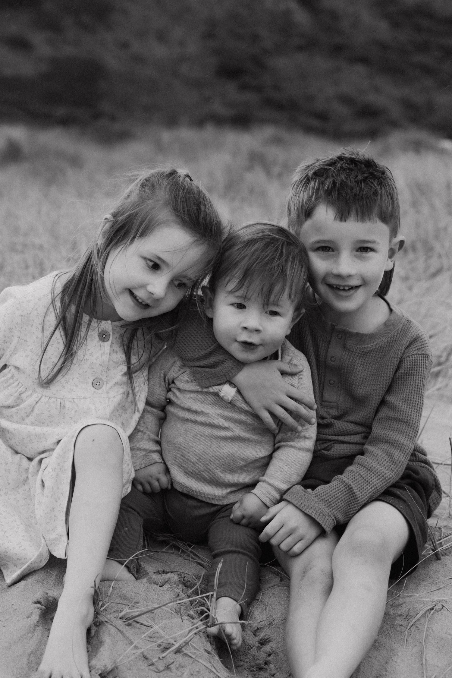 Black and white image showing playful children lying close together outdoors.