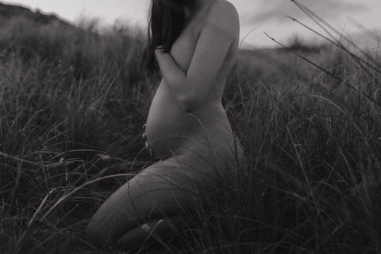 Artistic black and white portrait of figure among tall grass.