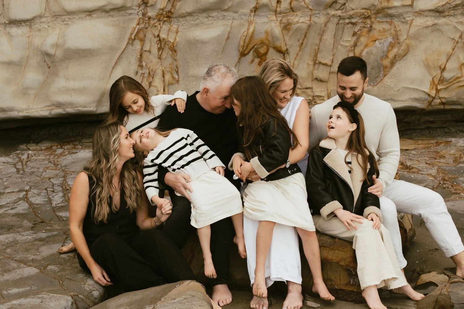 A family group laughing together while relaxing on rocky terrain.