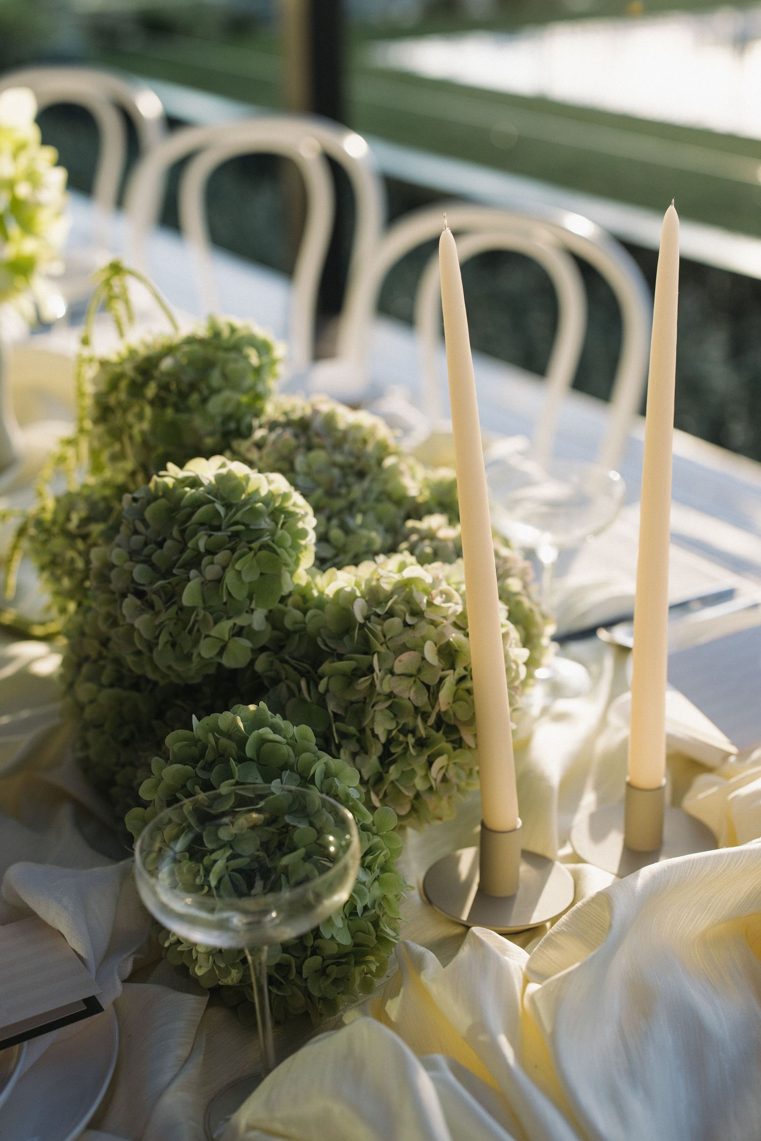 Elegant table setting with white candles and green hydrangea centerpieces at a wedding reception.