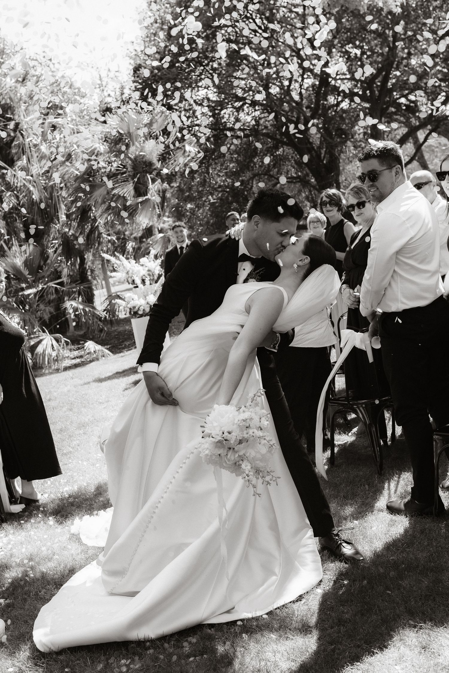 Wedding ceremony celebration captured in black and white with guests outdoors.