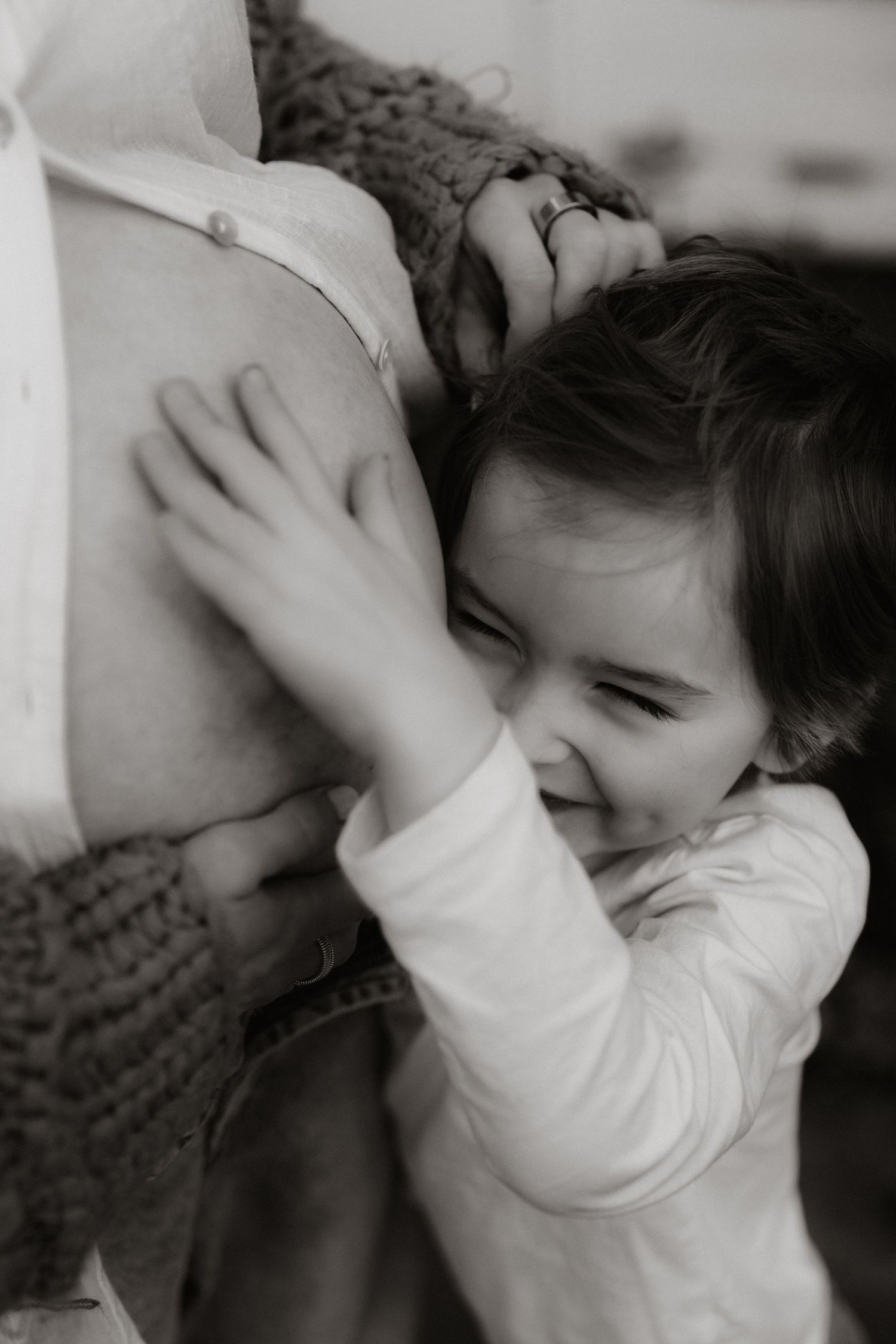 A series of black and white photos showing a baby in a white shirt reaching up to touch their face.