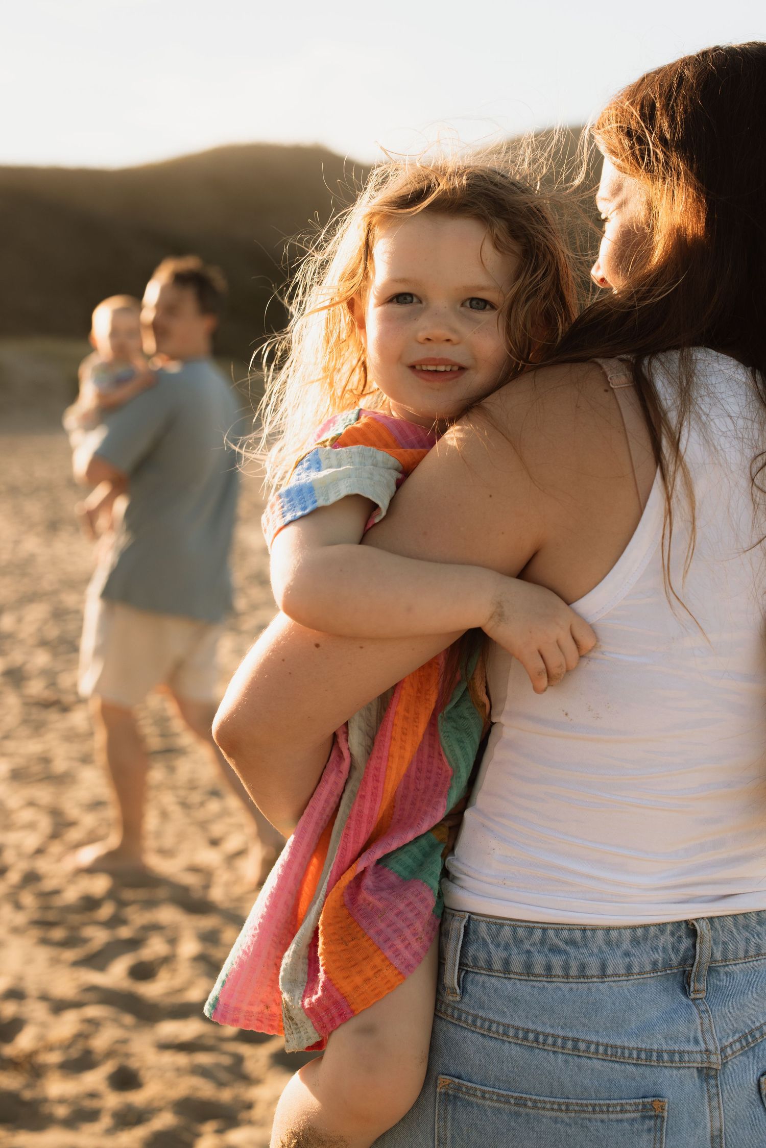 Warm sunset embrace on sandy beach with colorful summer clothing.