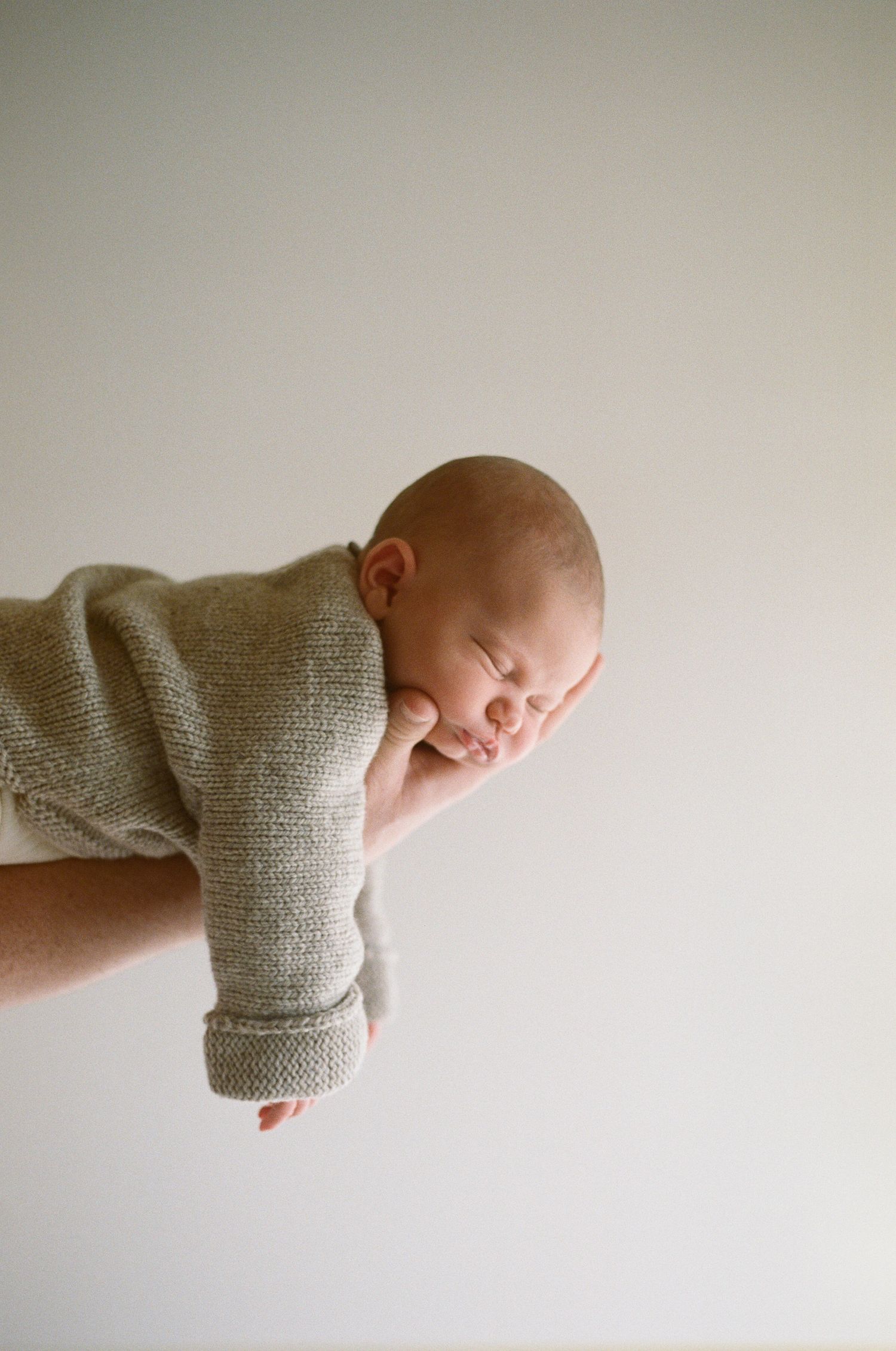 A series of minimalist photos showing a sleeping baby in a gray sweater against a white background.