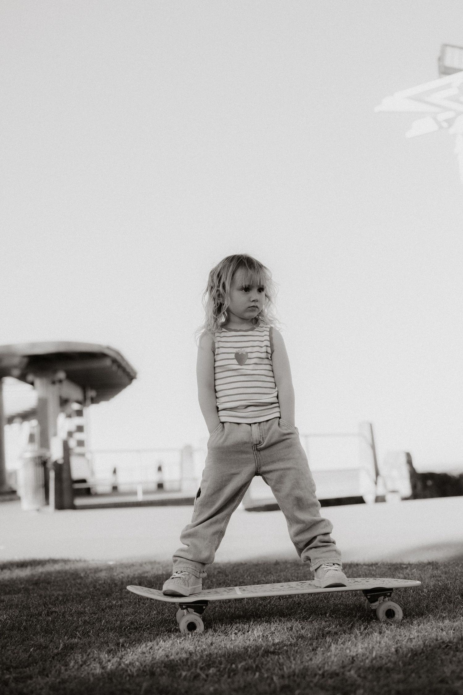 Small child stands on a skateboard against a bright background.