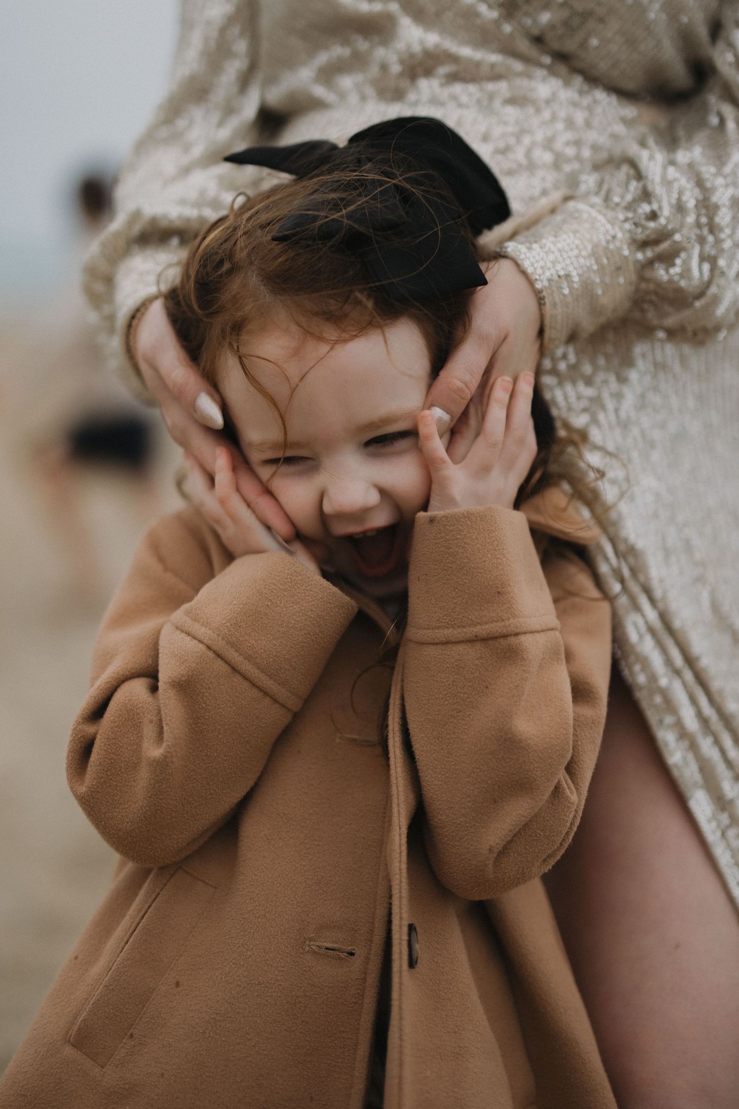 A playful expression captured in warm tones wearing a camel coat.