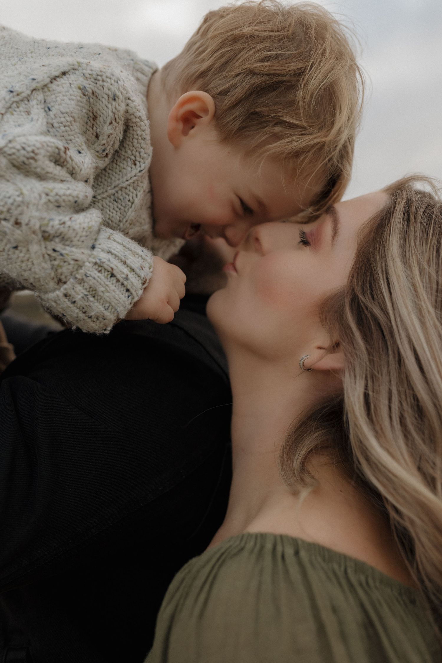 A sweet moment of affection captured in soft, moody lighting outdoors.