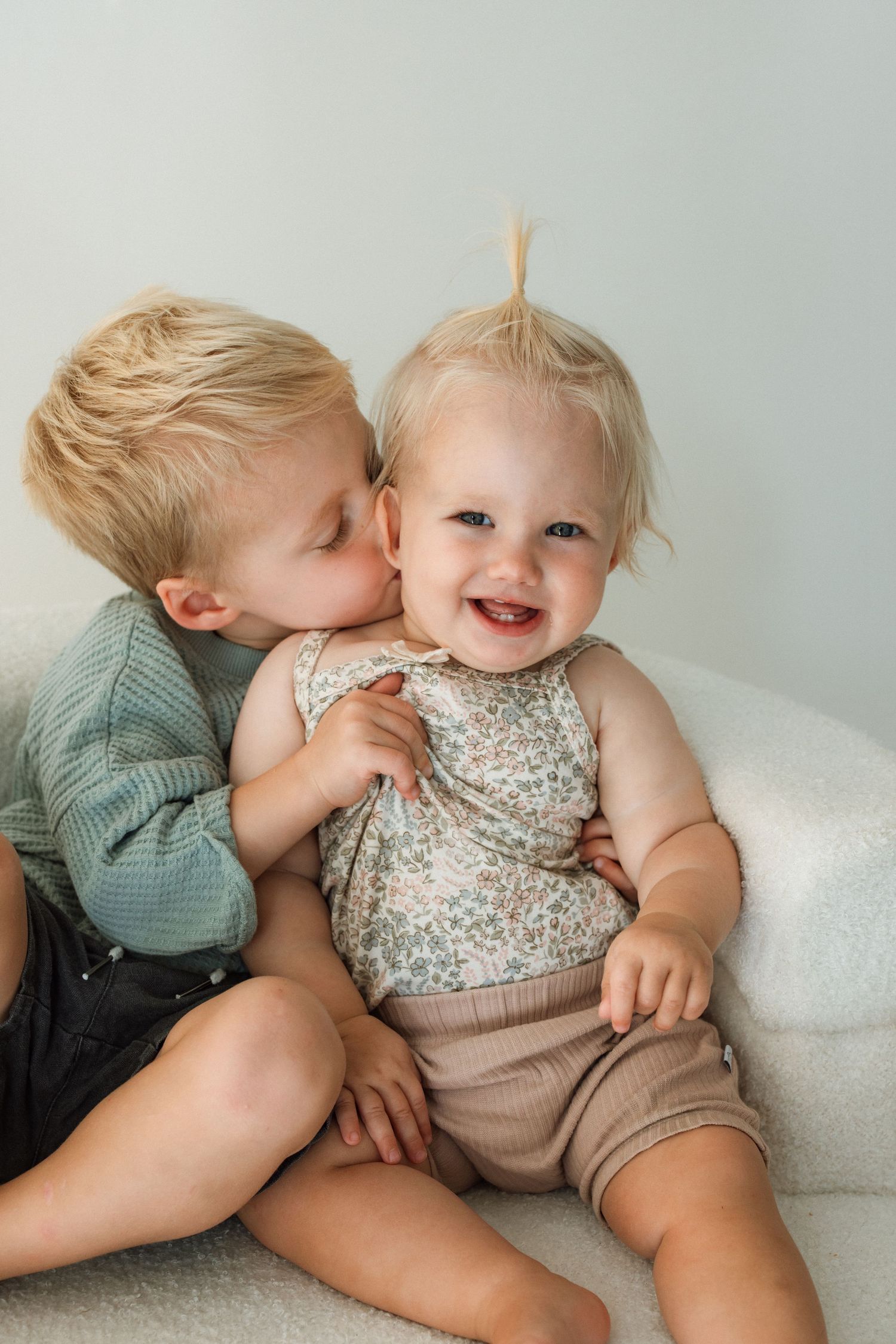 Sweet moment of sibling affection on a light colored sofa.