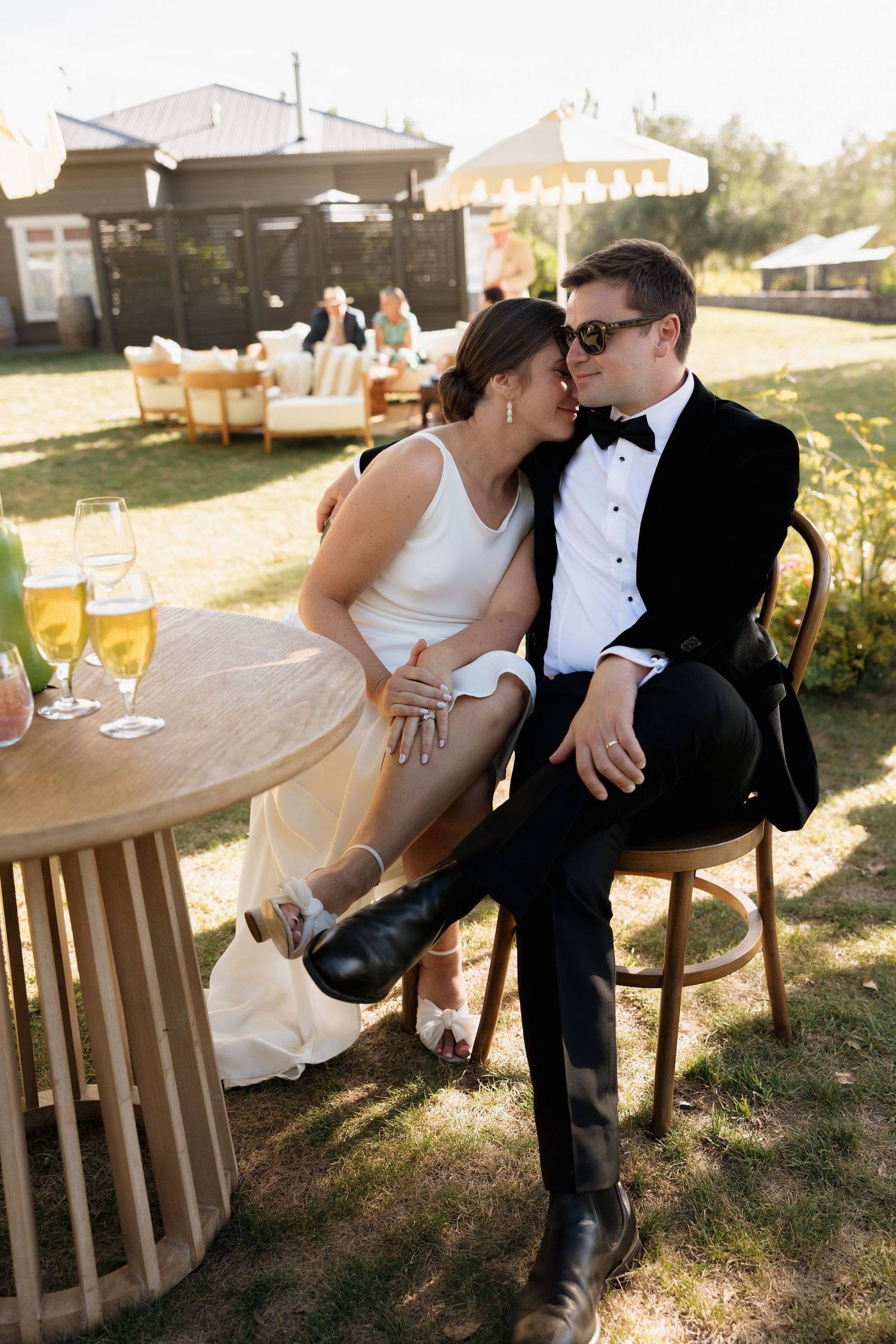 Romantic couple shares intimate moment at outdoor wedding reception with rustic decor.