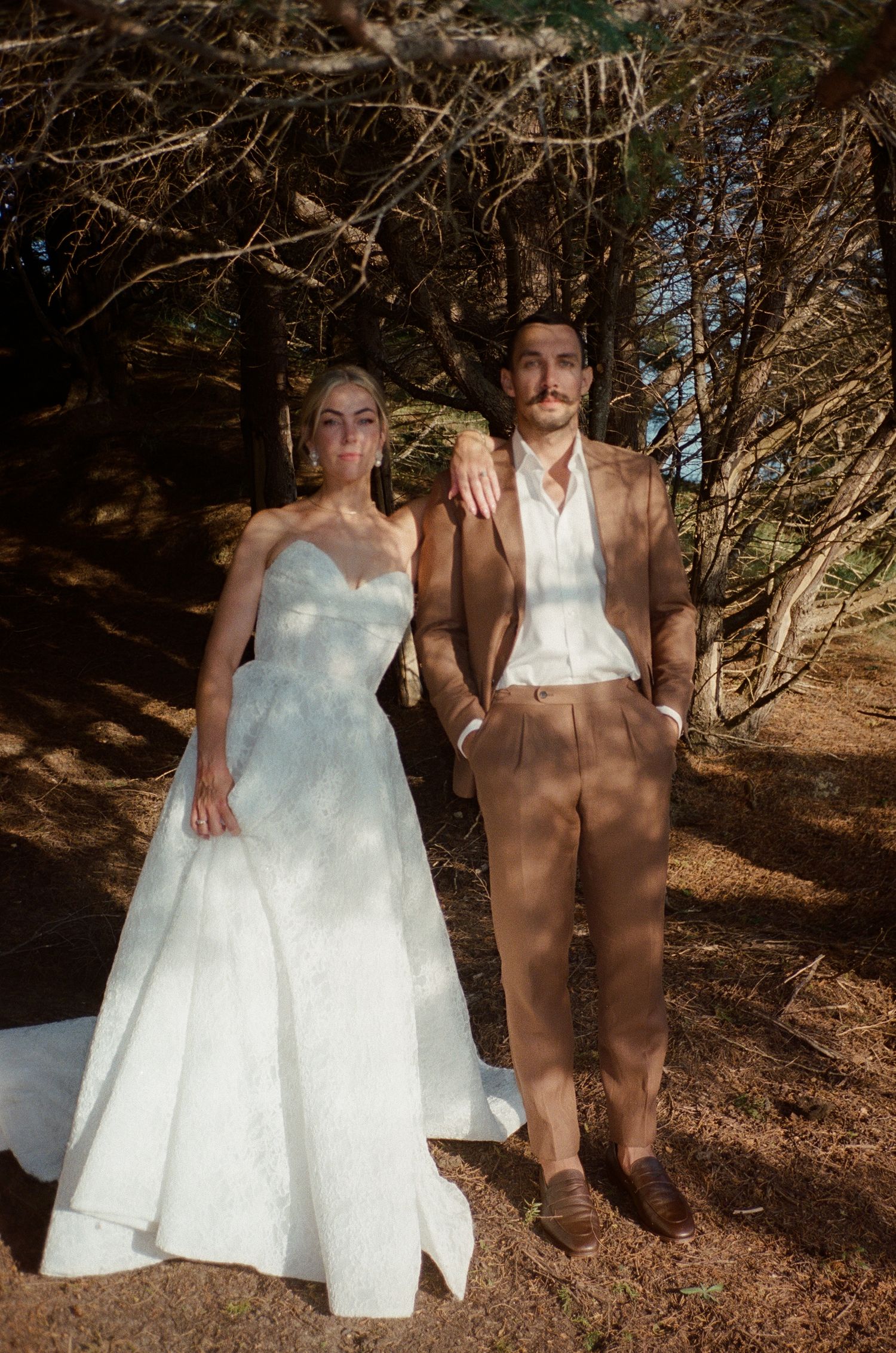 Two figures in a wooded area, one wearing a white dress and the other in brown attire.