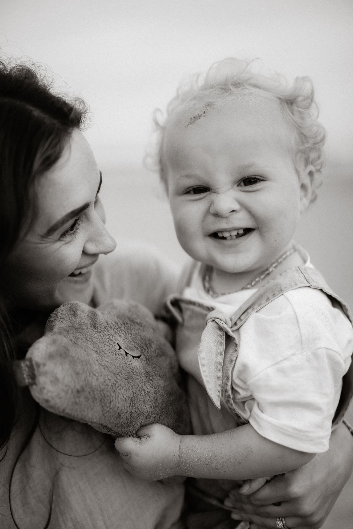 A heartwarming black and white series of photos showing joyful interactions between a child and stuffed teddy bear.