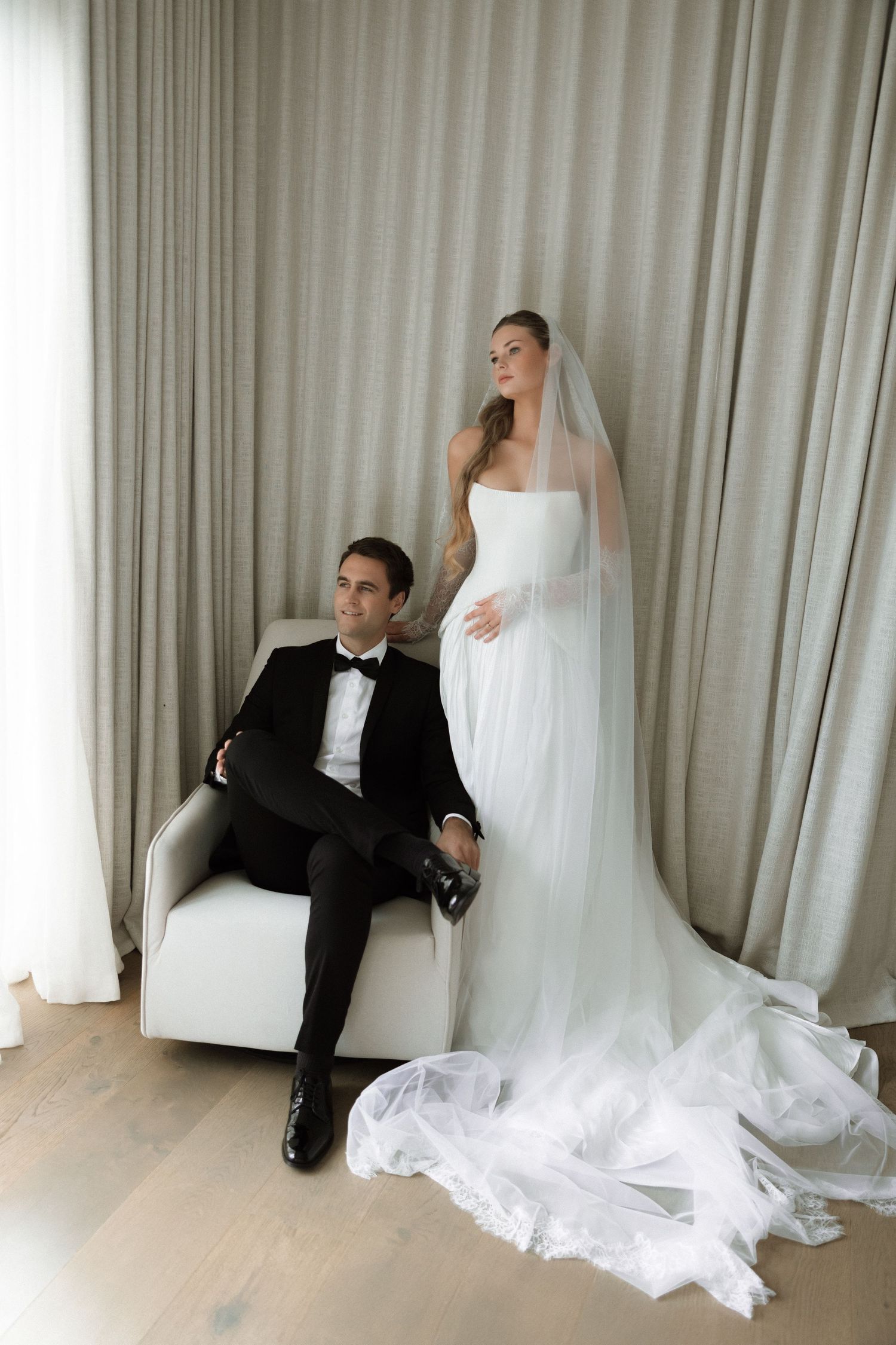 Wedding photoshoot with couple creating dynamic poses against light curtain backdrop.