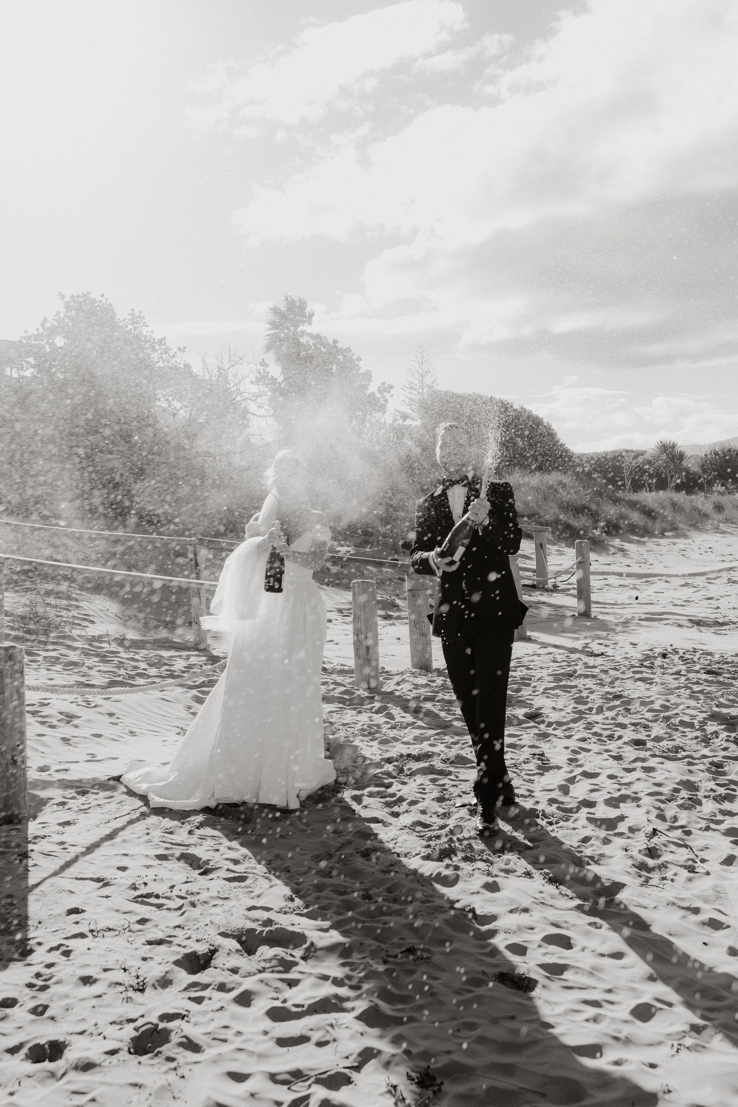 Wedding couple walking along a sandy beach path in black and white photography.