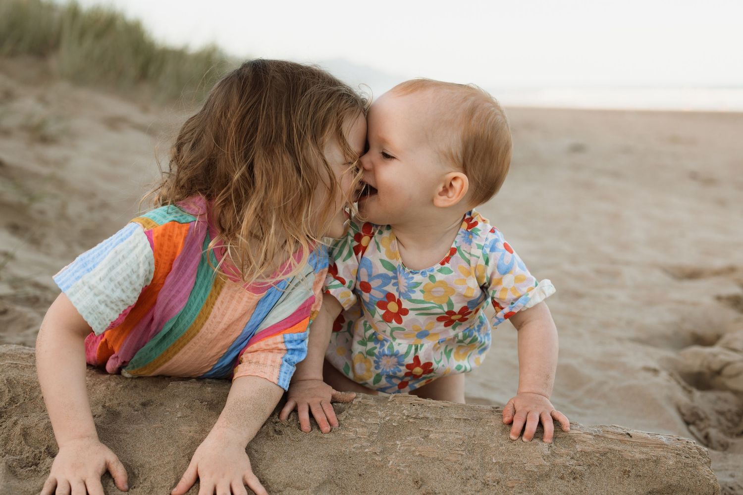 Close interaction on sandy beach with vibrant patterns in clothing.