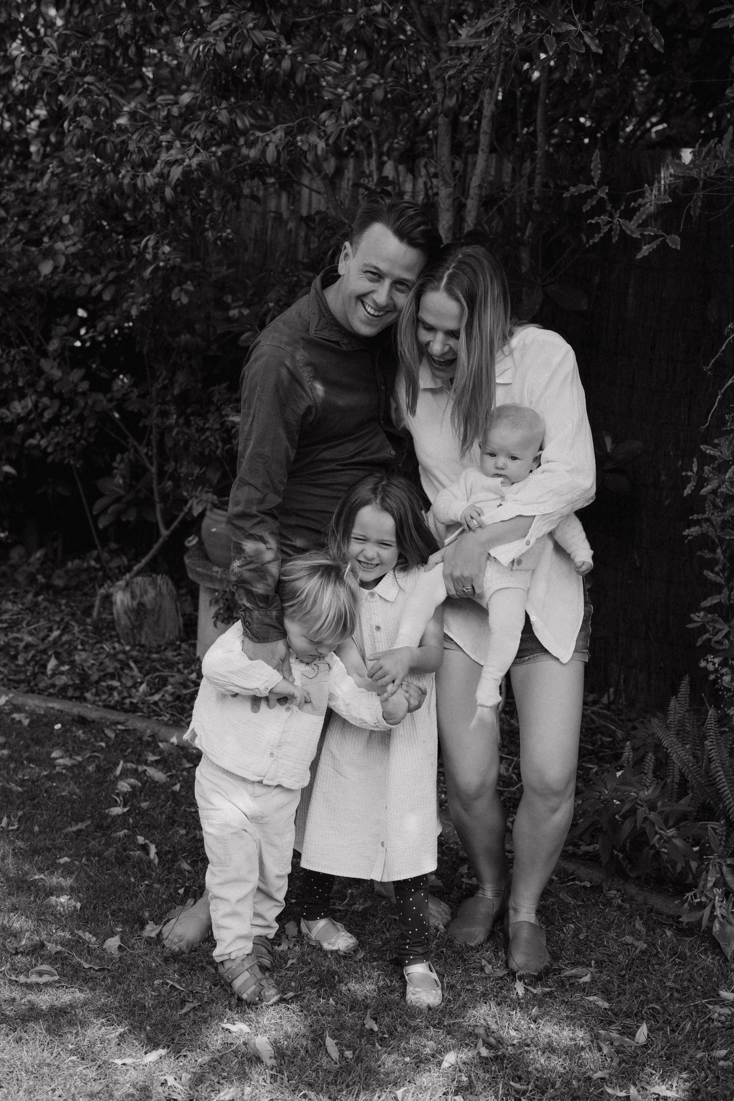 A sequence of black and white photos shows a parent and child playing together outdoors in a garden.