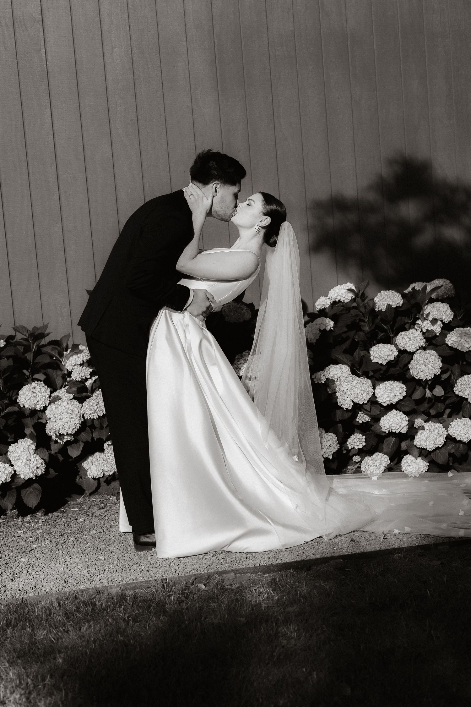 Romantic black and white wedding photos by hydrangea bushes.